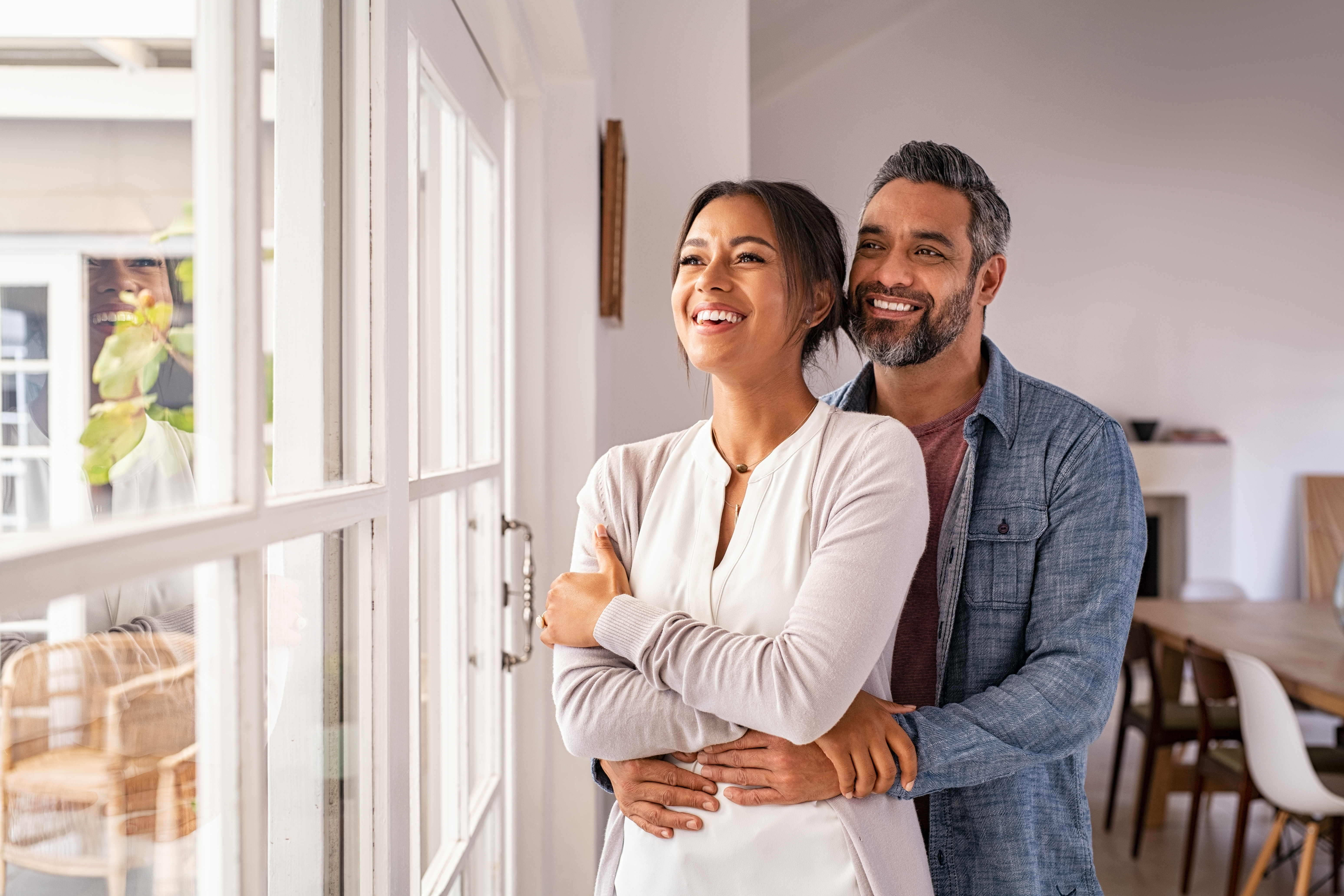 Un mari et sa femme sourient en regardant par la fenêtre | Source : Shutterstock