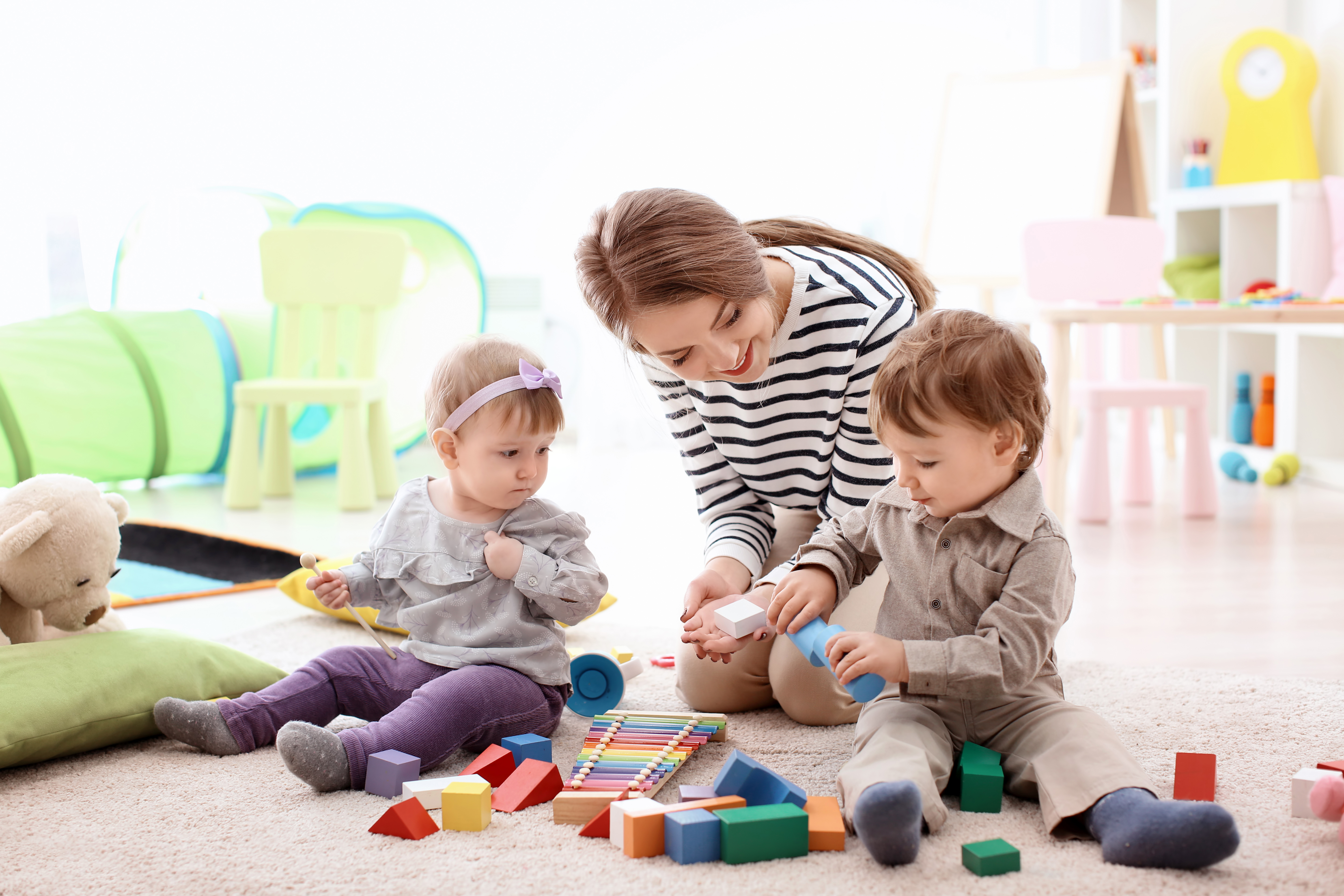 Une jeune femme assiste deux bambins pendant la récréation | Source : Shutterstock