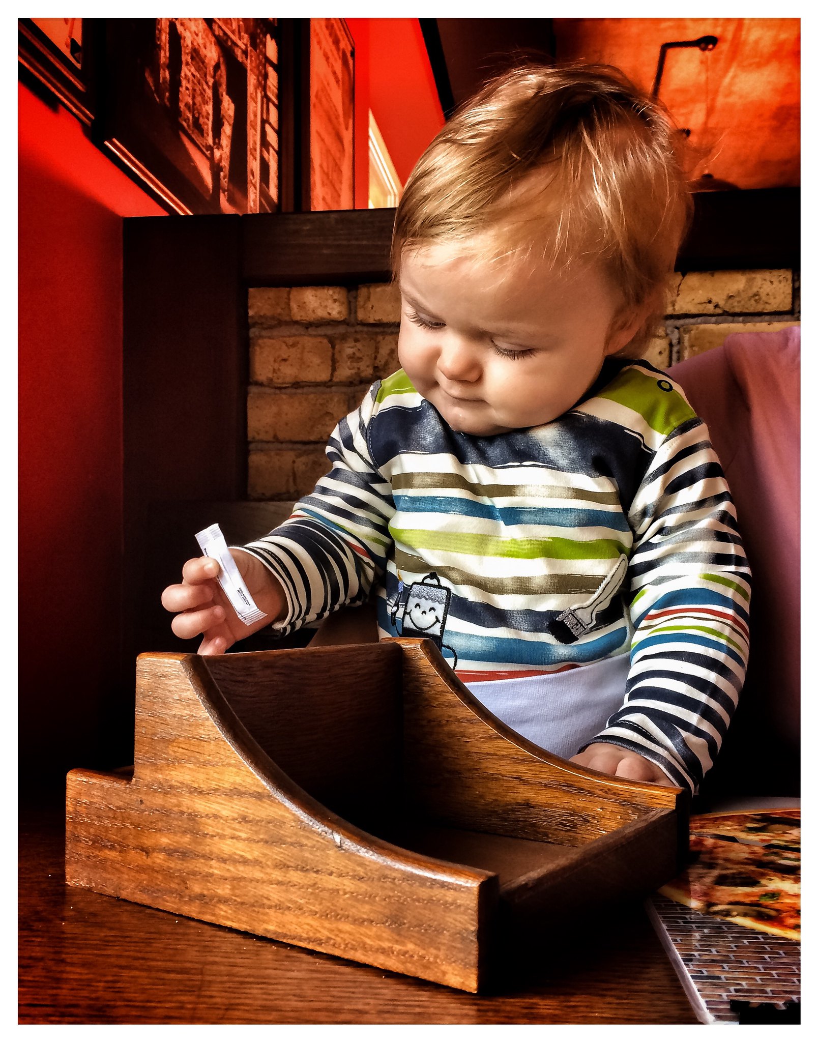 Un petit garçon qui joue avec un sachet de sucre dans un restaurant | Source : Flickr
