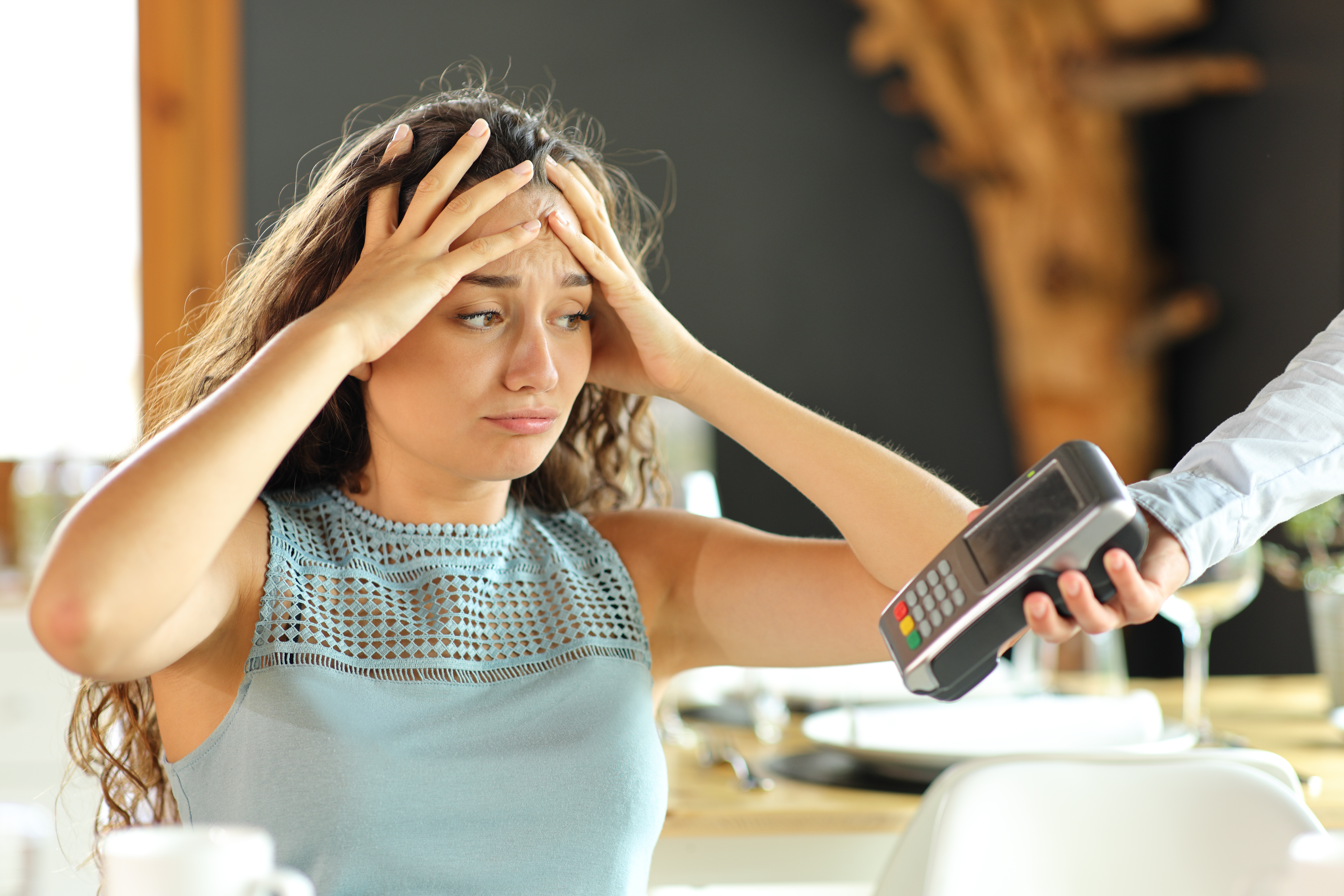 Une femme a l'air désespérée alors qu'on lui tend un distributeur de cartes de crédit. | Source : Shutterstock