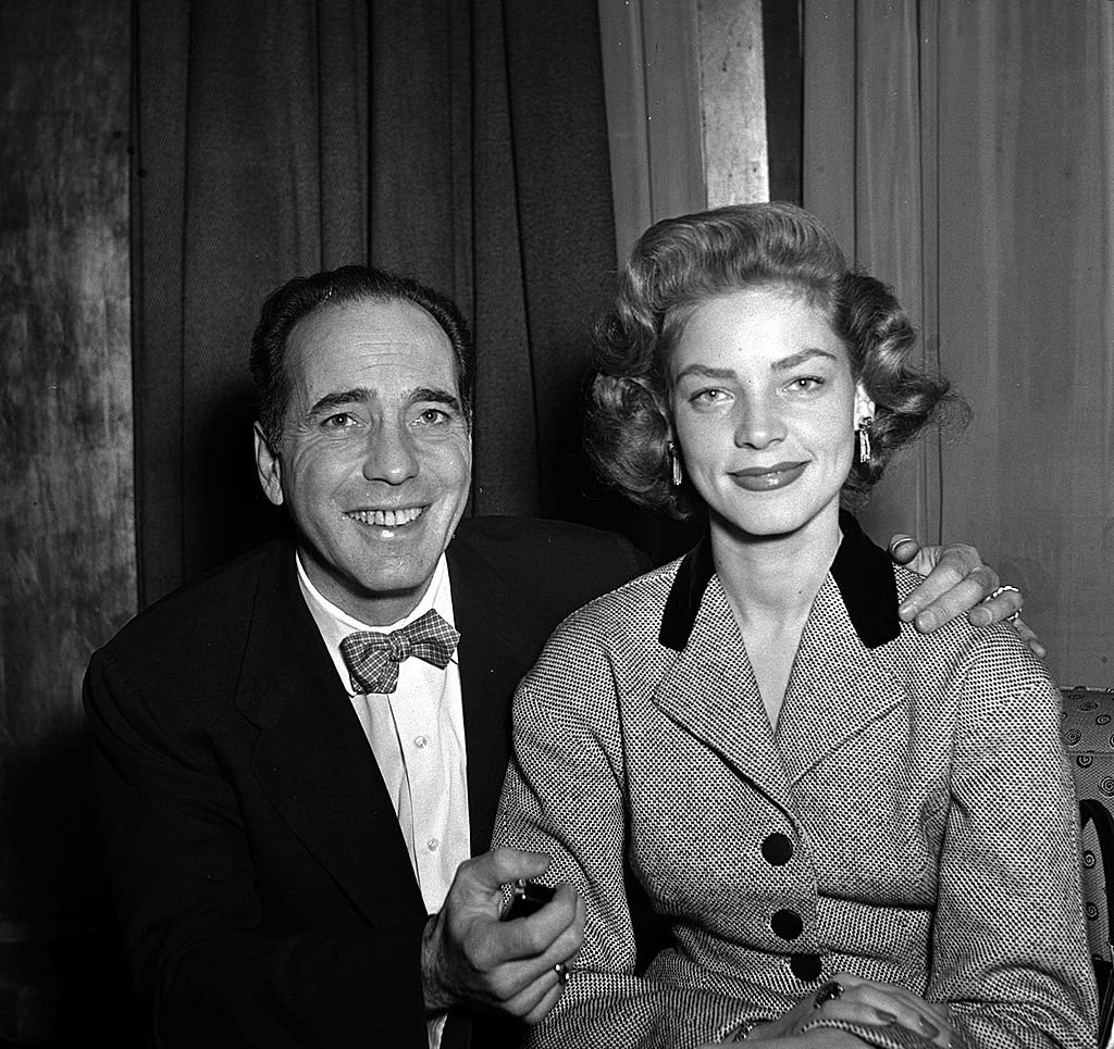 Humphrey Bogart sourit avec sa femme actrice Lauren Bacall lors d'une réception de presse au Claridges à Londres, 1951 | Photo : Getty Images