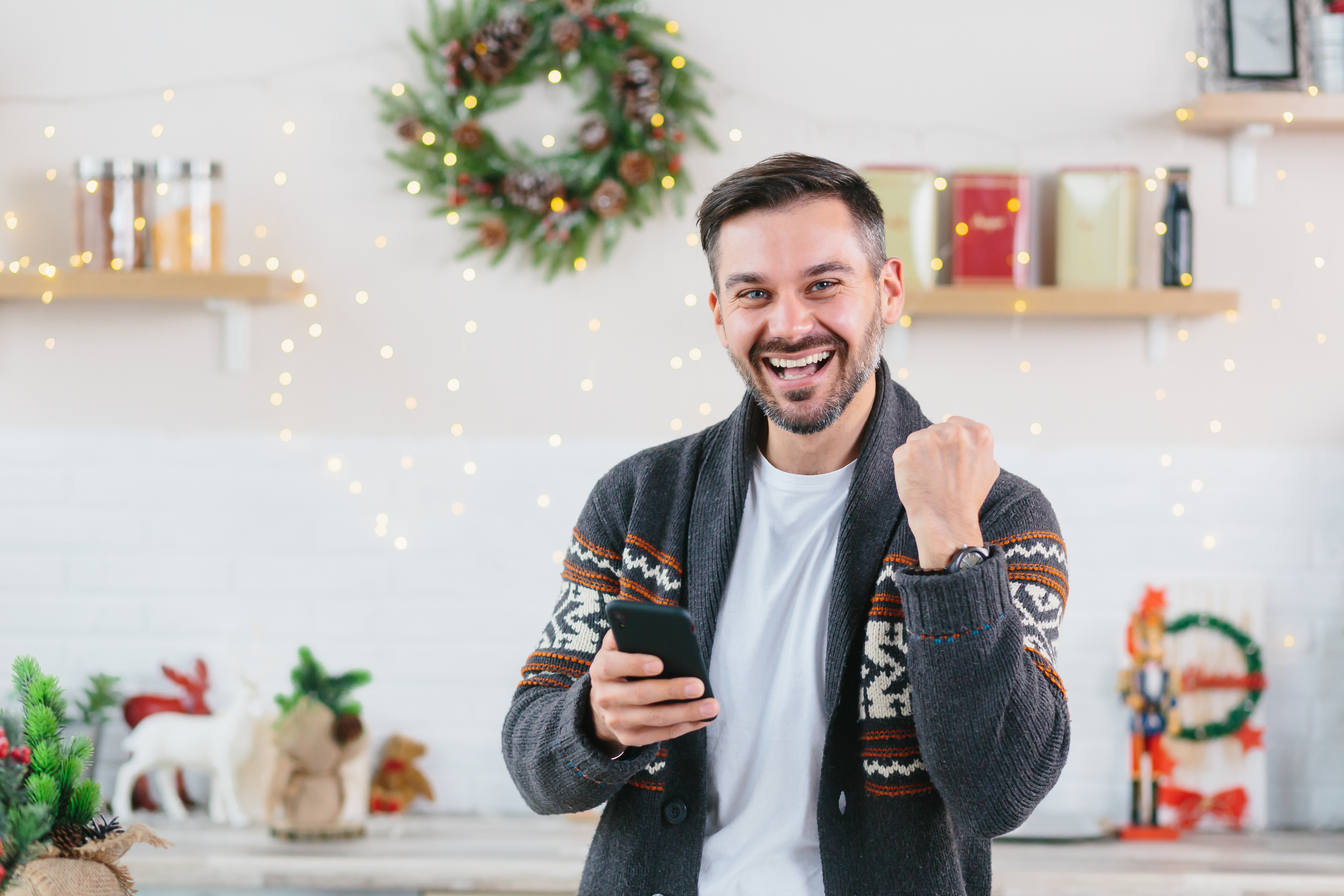 Jeune homme célébrant une victoire à la maison pendant Noël | Source : Shutterstock