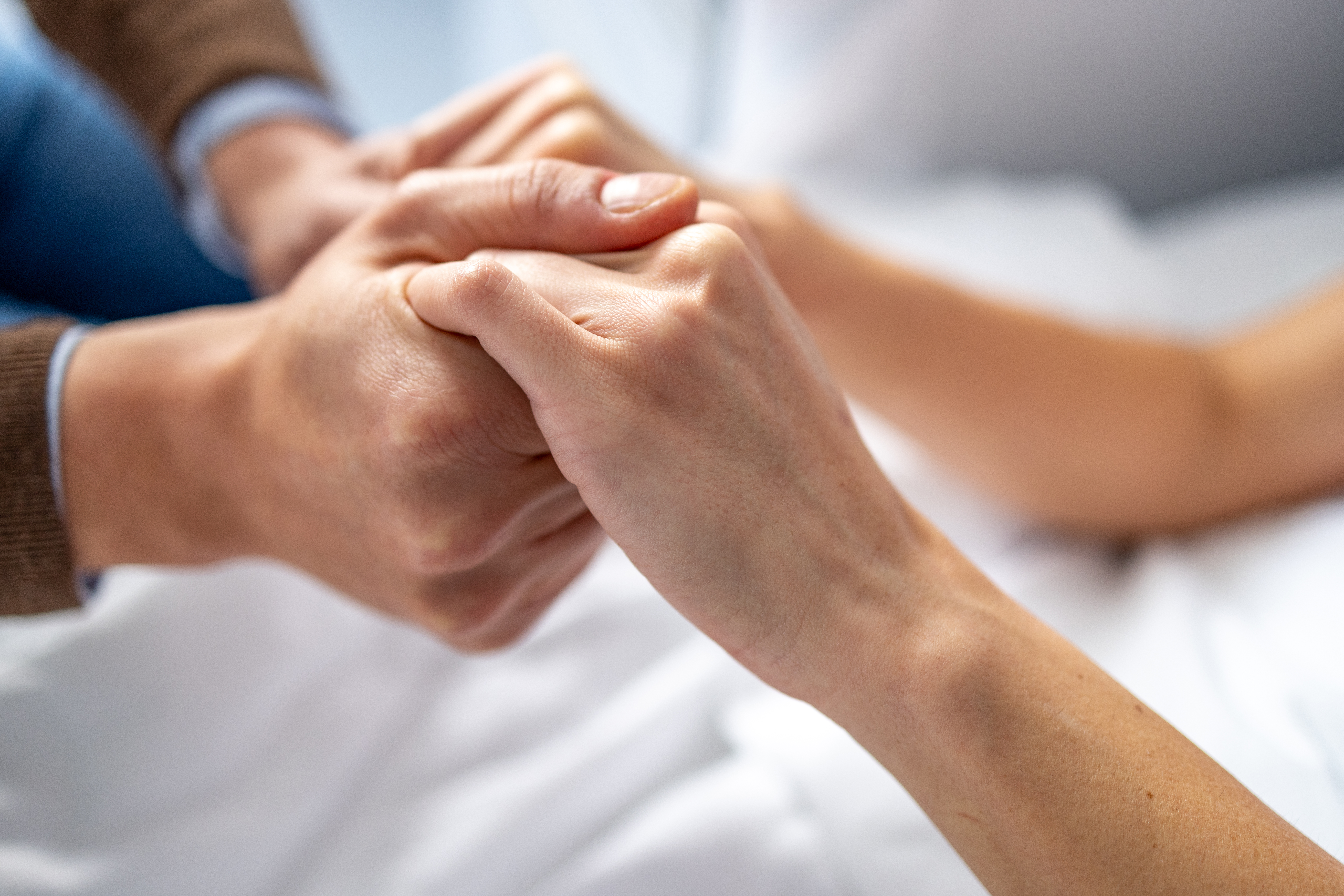 Homme tenant la main d'une femme dans un lit d'hôpital. | Source : Getty Images