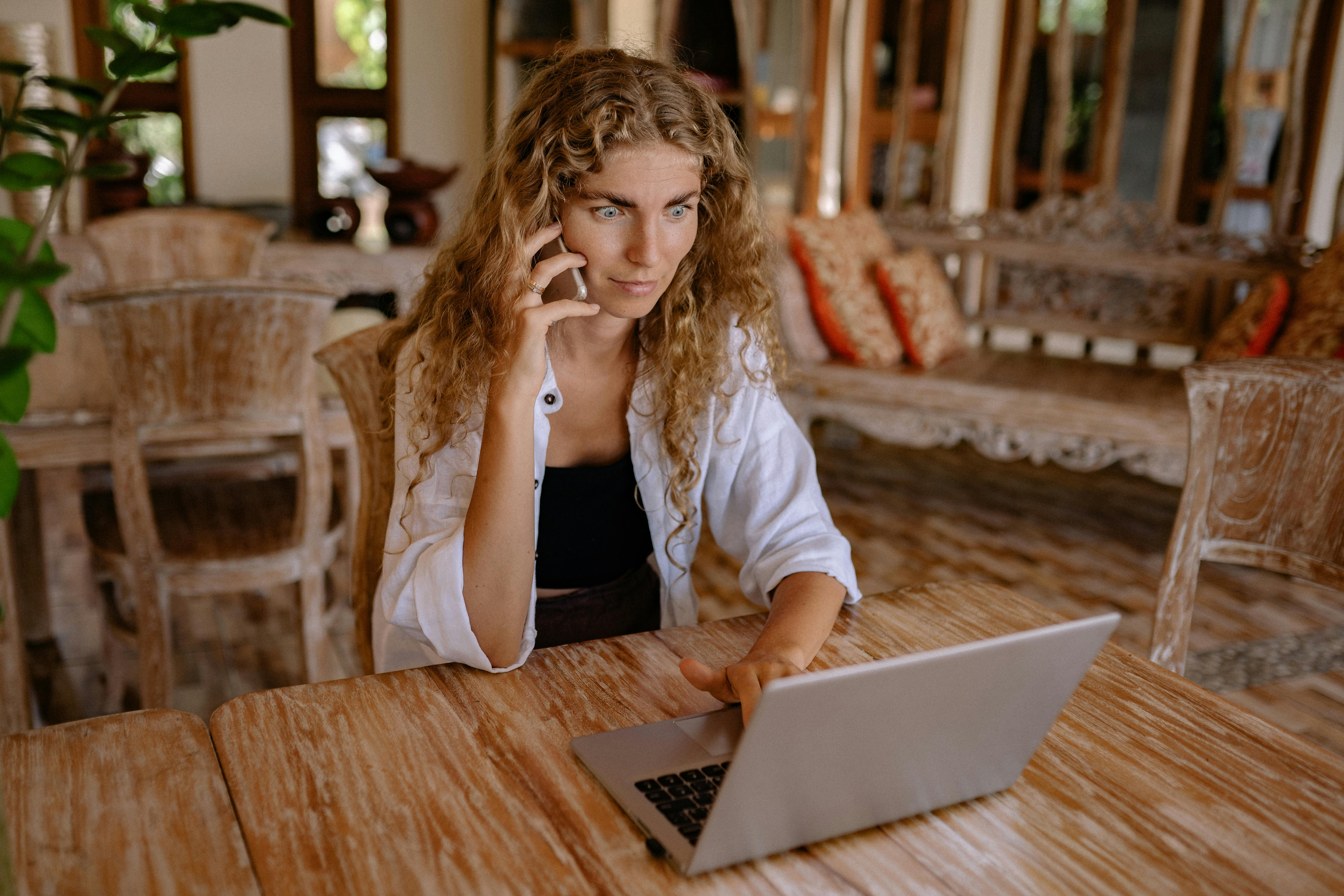 Une femme en train de téléphoner tout en utilisant un ordinateur portable | Source : Pexels