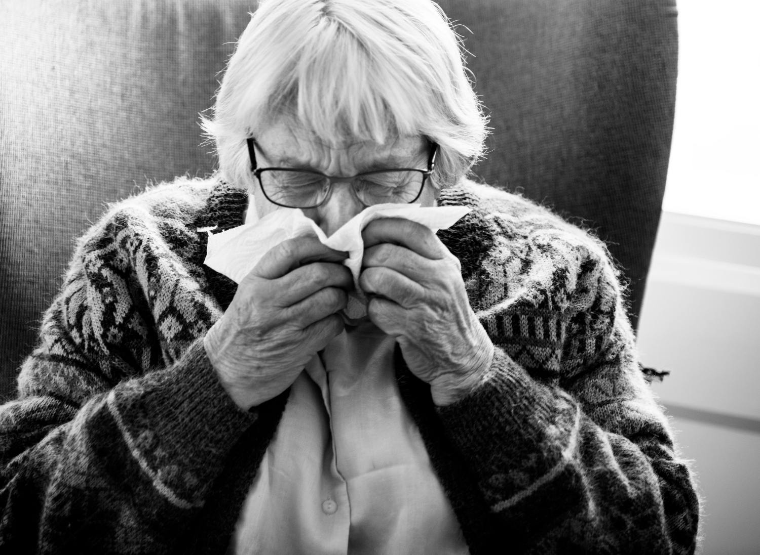 Plan en niveaux de gris d'une femme âgée utilisant son mouchoir | Source : Freepik