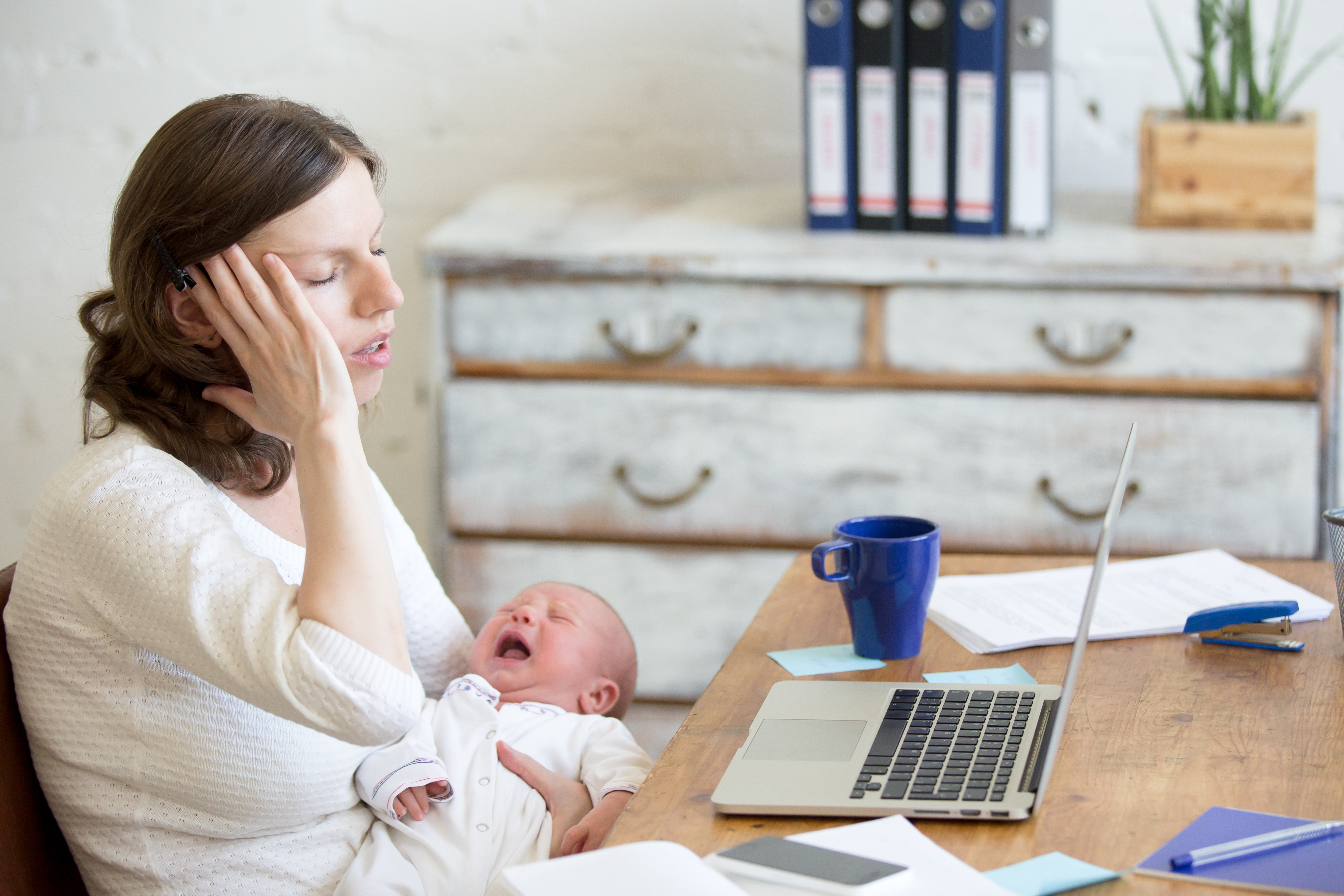 Une femme a l'air stressée alors qu'elle tient un nouveau-né en pleurs | Source : Shutterstock