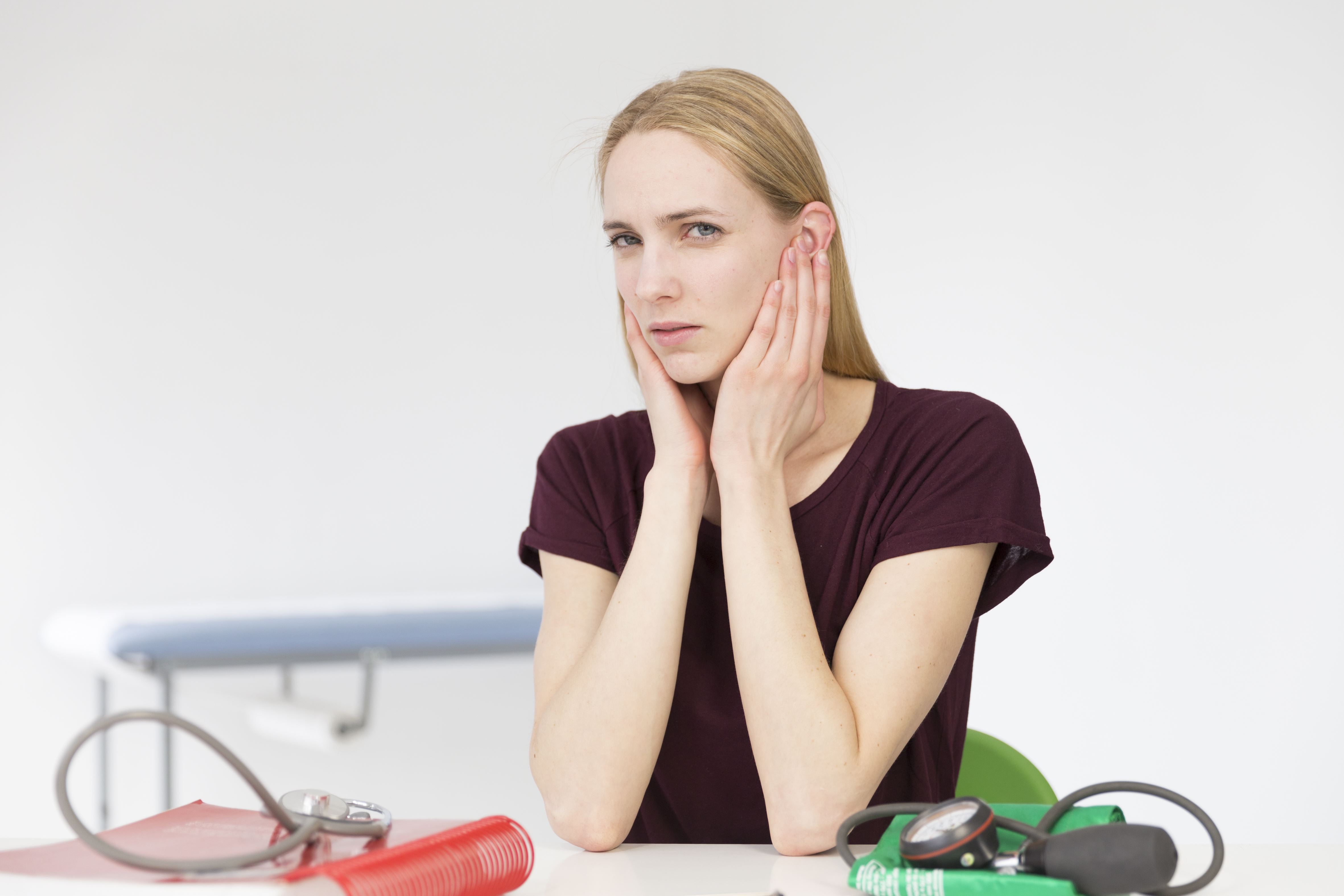 Femme en gêne visible discutant des symptômes de l'otite lors d'une consultation | Source : Getty Images