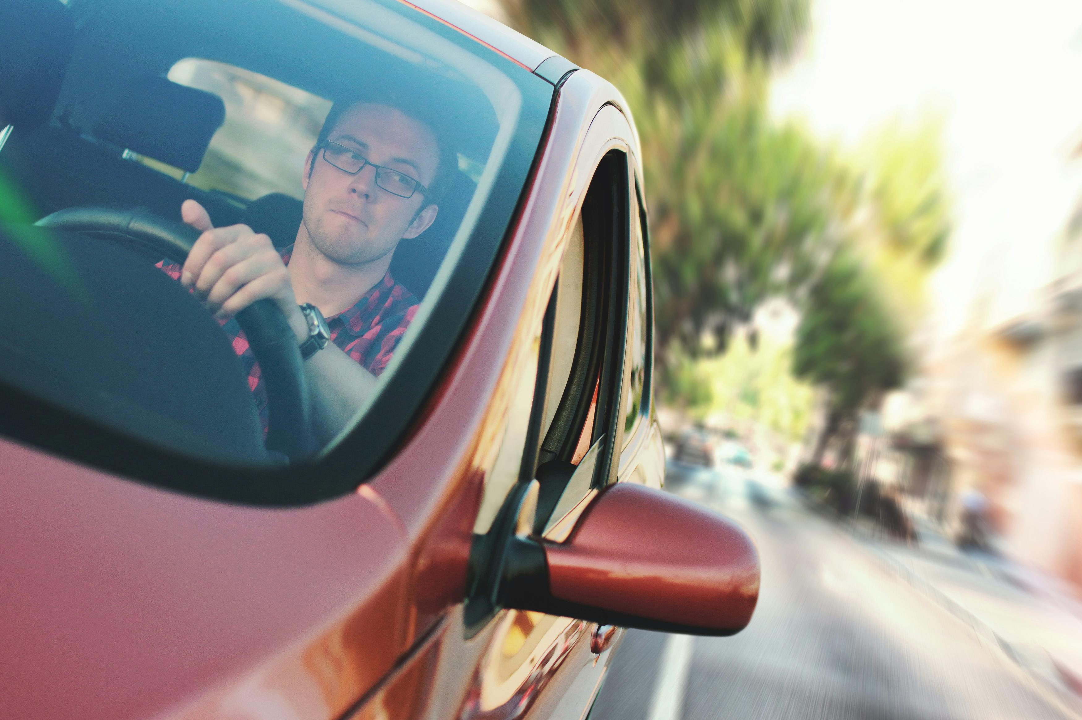 Un homme conduisant une voiture rouge | Source : Pexels