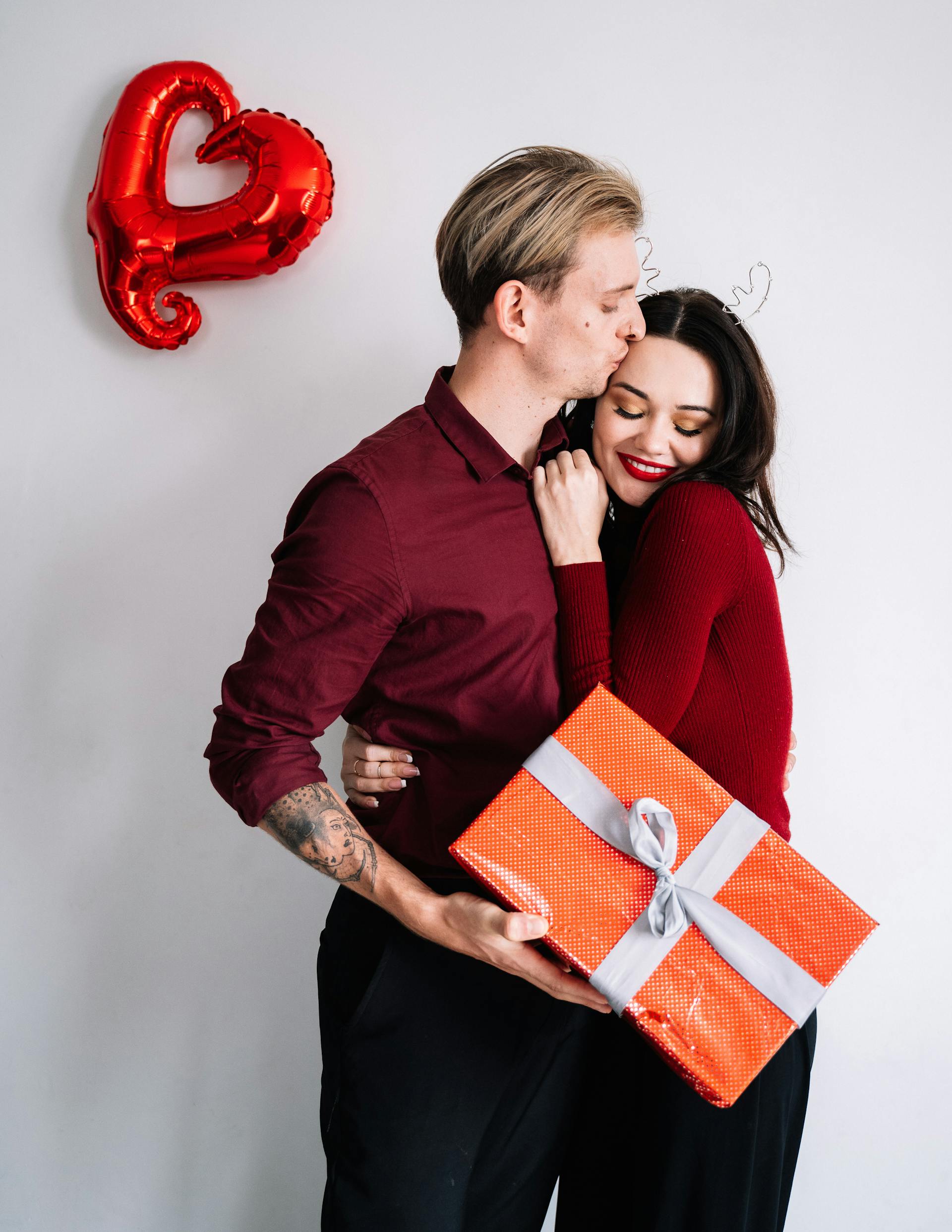 Un homme embrassant une femme tout en tenant un paquet cadeau | Source : Pexels