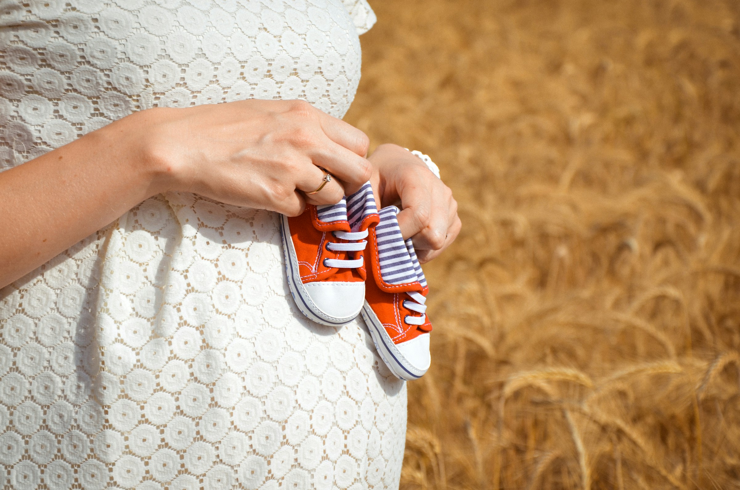 Une femme enceinte tenant de minuscules chaussures de bébé | Source : Unsplash