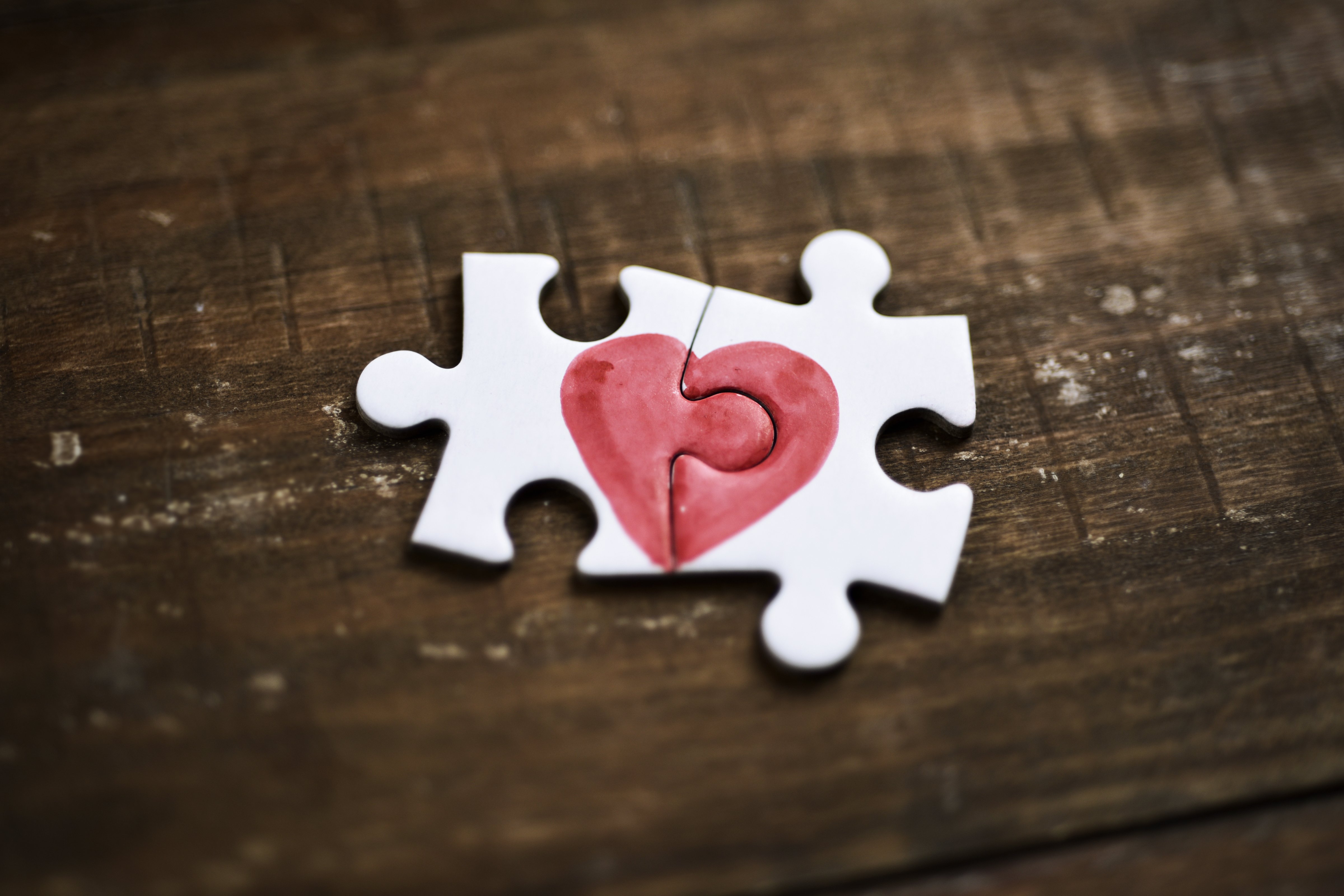 Gros plan de deux pièces d'un puzzle formant un cœur sur une surface en bois rustique, illustrant l'idée que l'amour est une chose à deux. │Source : Shutterstock