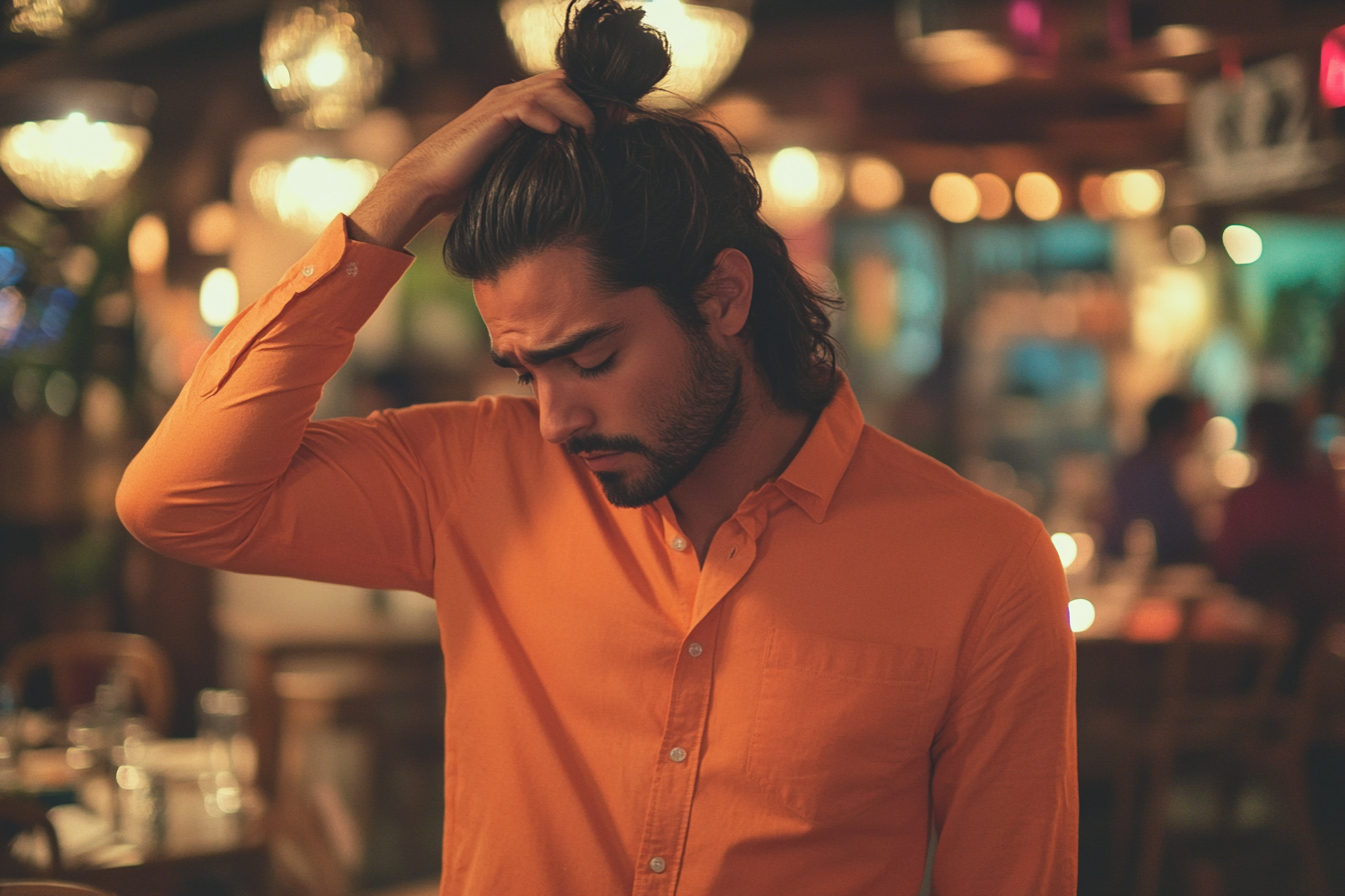 A man standing in a restaurant, touching his hair, looking sad and tired | Source: Midjourney