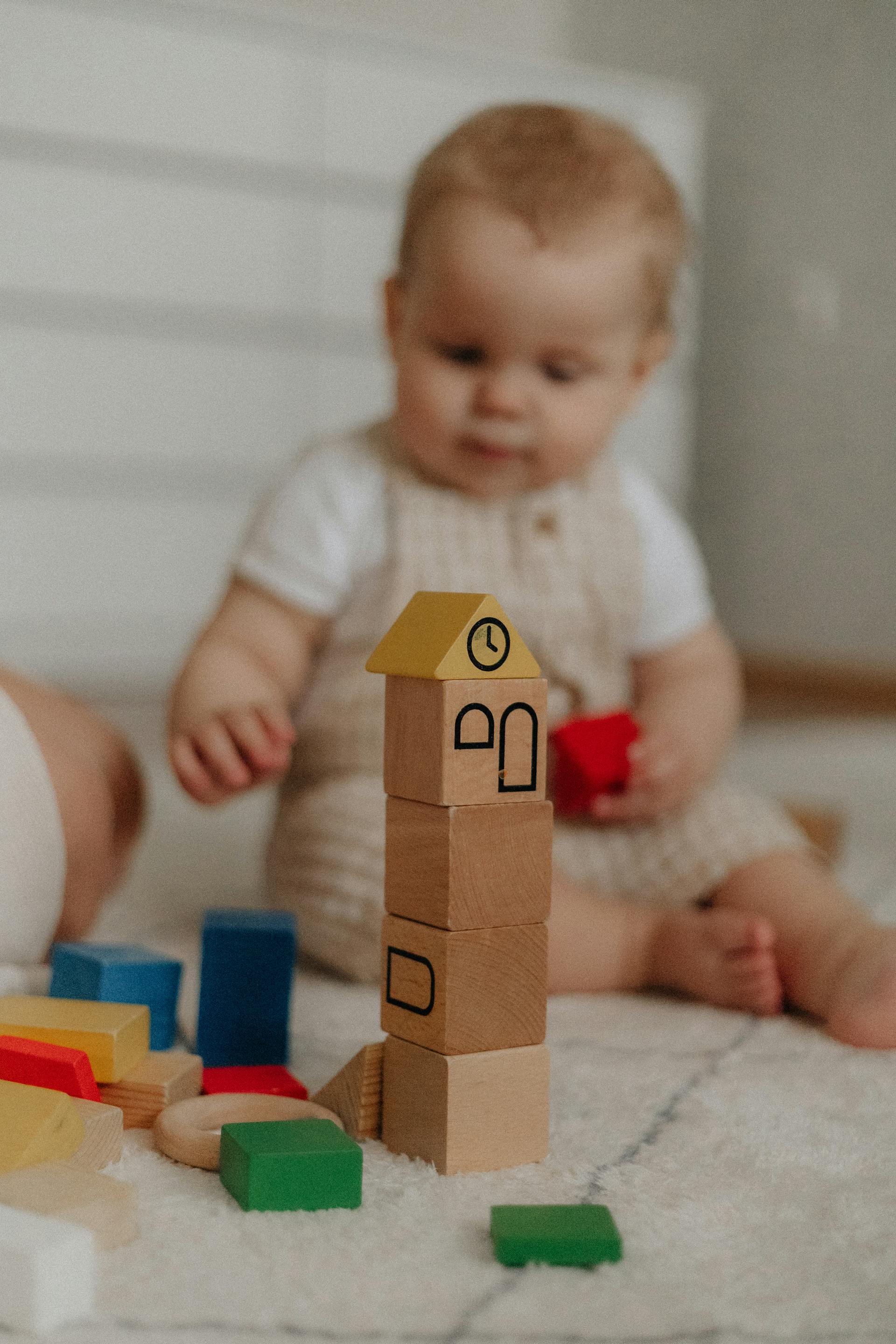 Un bébé assis sur le tapis et jouant avec des blocs | Source : Pexels