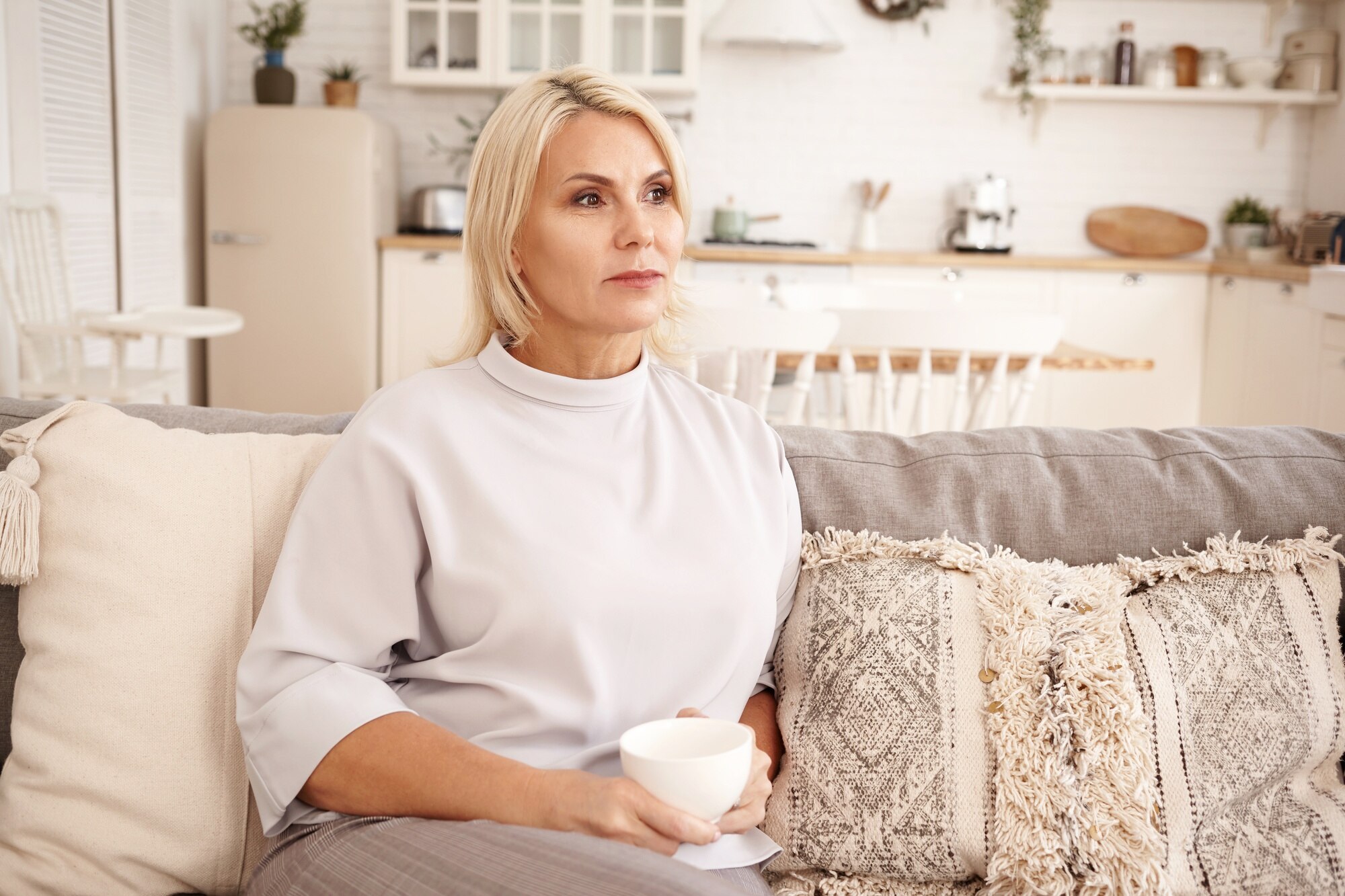 Une femme à l'expression sérieuse assise sur un canapé | Source : Freepik