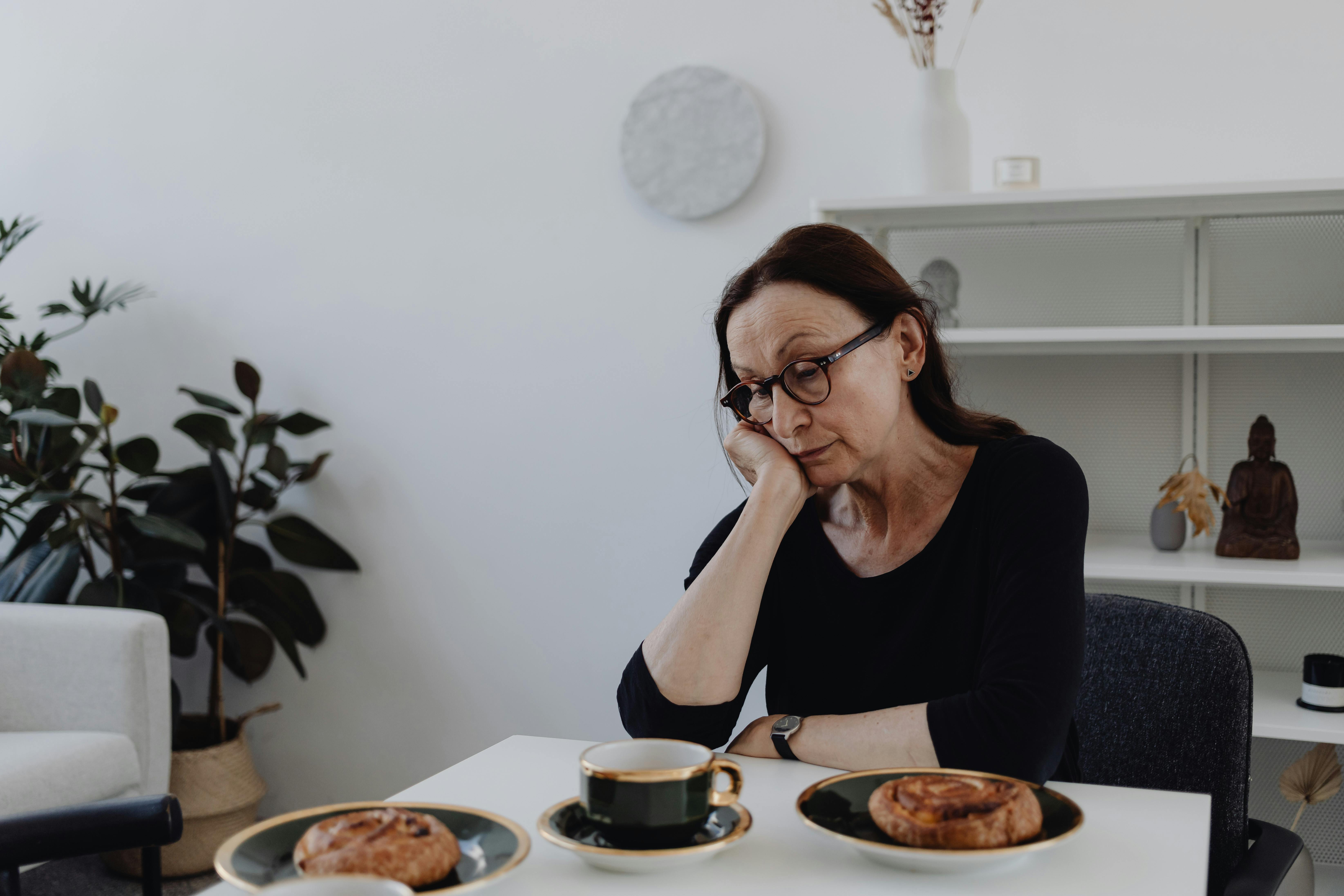 Une femme âgée assise à une table avec du thé et des collations | Source : Pexels