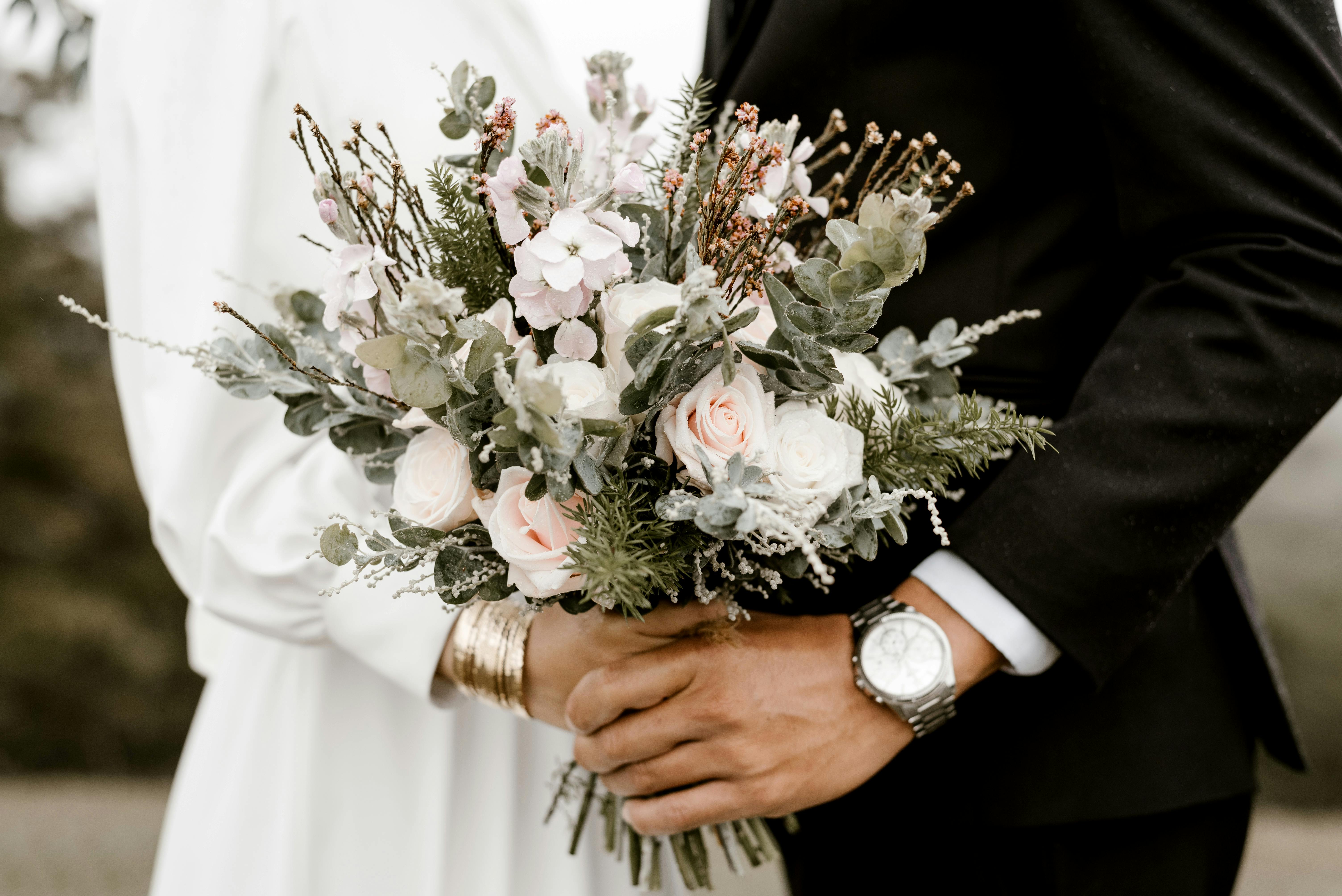 Le marié et la mariée dansent en tenant un bouquet de mariage | Source : Pexels
