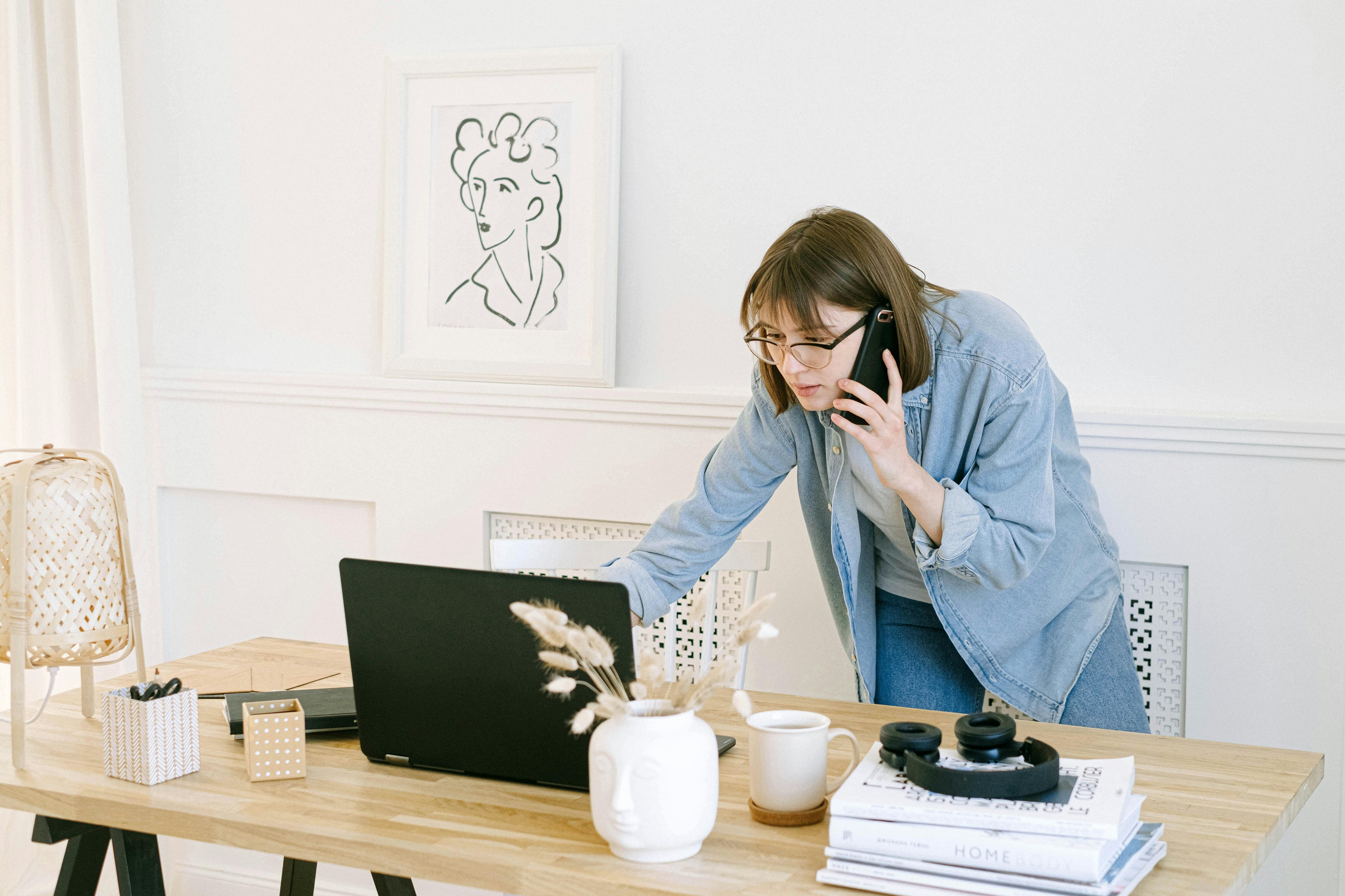 Femme parlant au téléphone tout en regardant un ordinateur portable | Source : Pexels