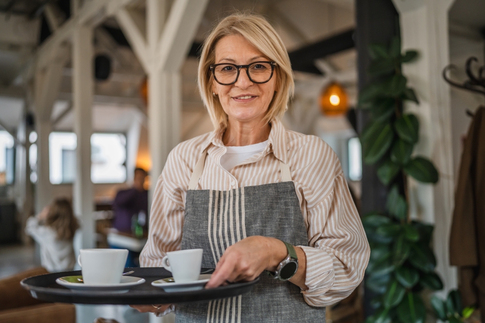 Une jolie serveuse d'âge mûr en tablier | Source : Shutterstock