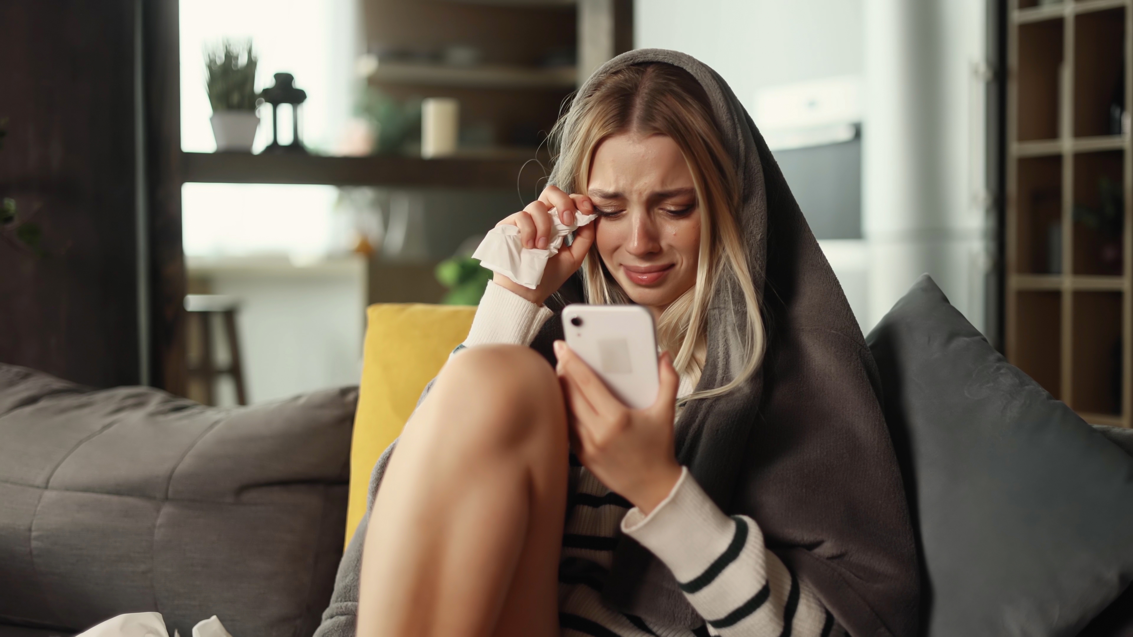 Jeune femme qui pleure en utilisant son téléphone | Source : Shutterstock