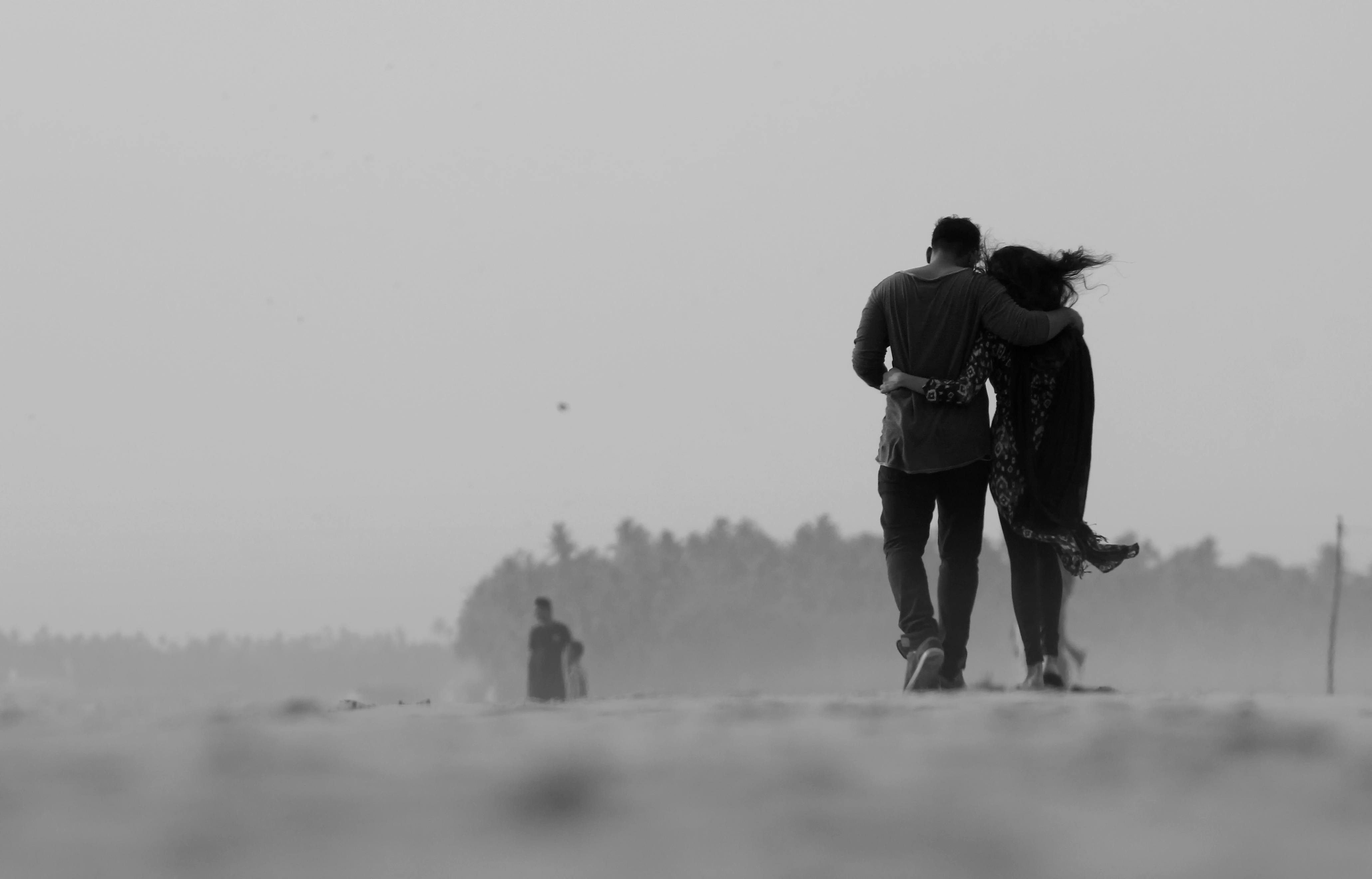 Une photo en noir et blanc d'un couple appuyé l'un sur l'autre et s'éloignant de l'appareil photo | Source : Pexels