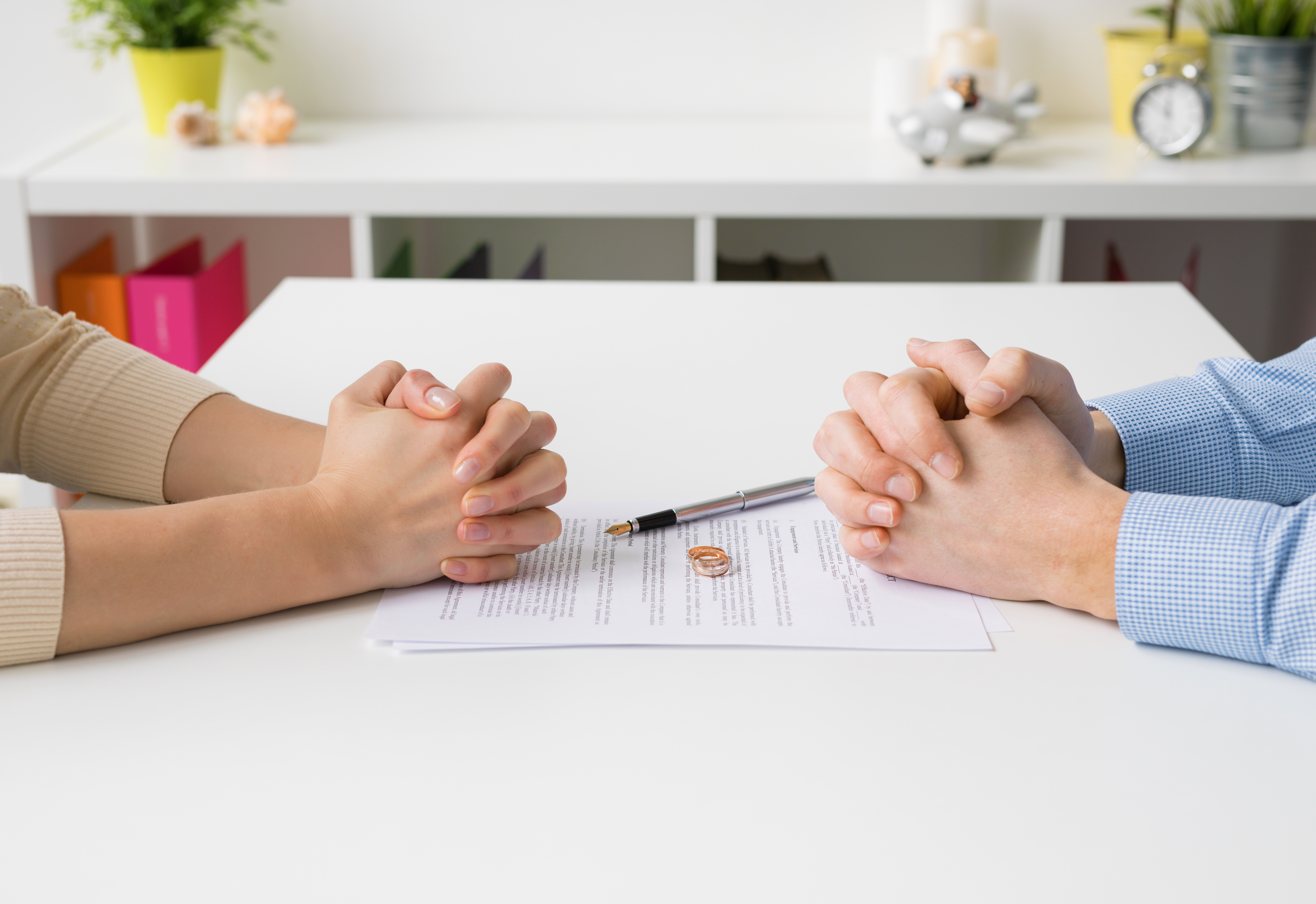 Les mains d'un homme et d'une femme posées sur une table, avec leurs alliances et les papiers du divorce devant eux : Shutterstock