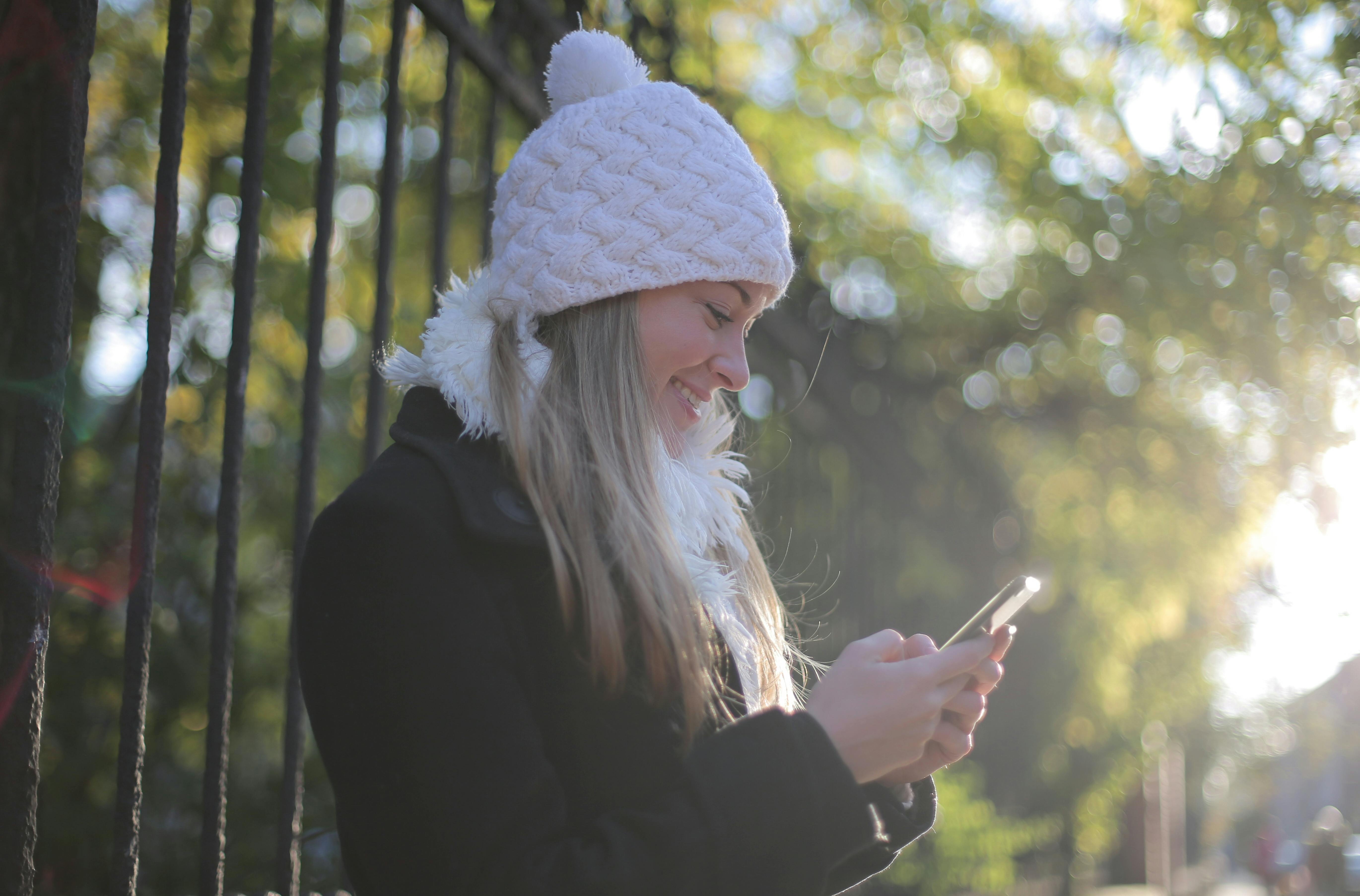 Une femme qui sourit en regardant son téléphone | Source : Pexels