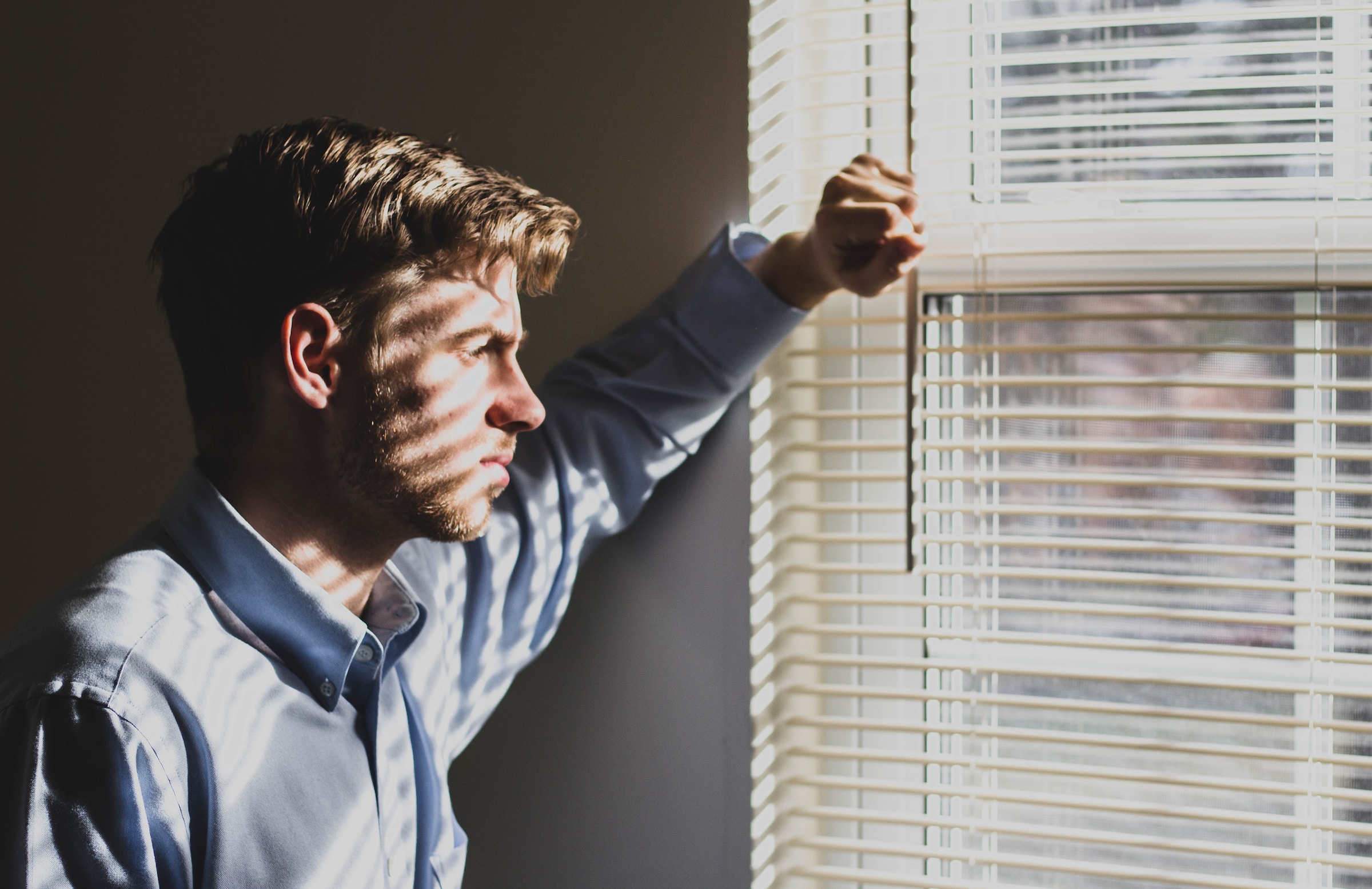 Un homme désemparé debout regardant par la fenêtre | Source : Unsplash