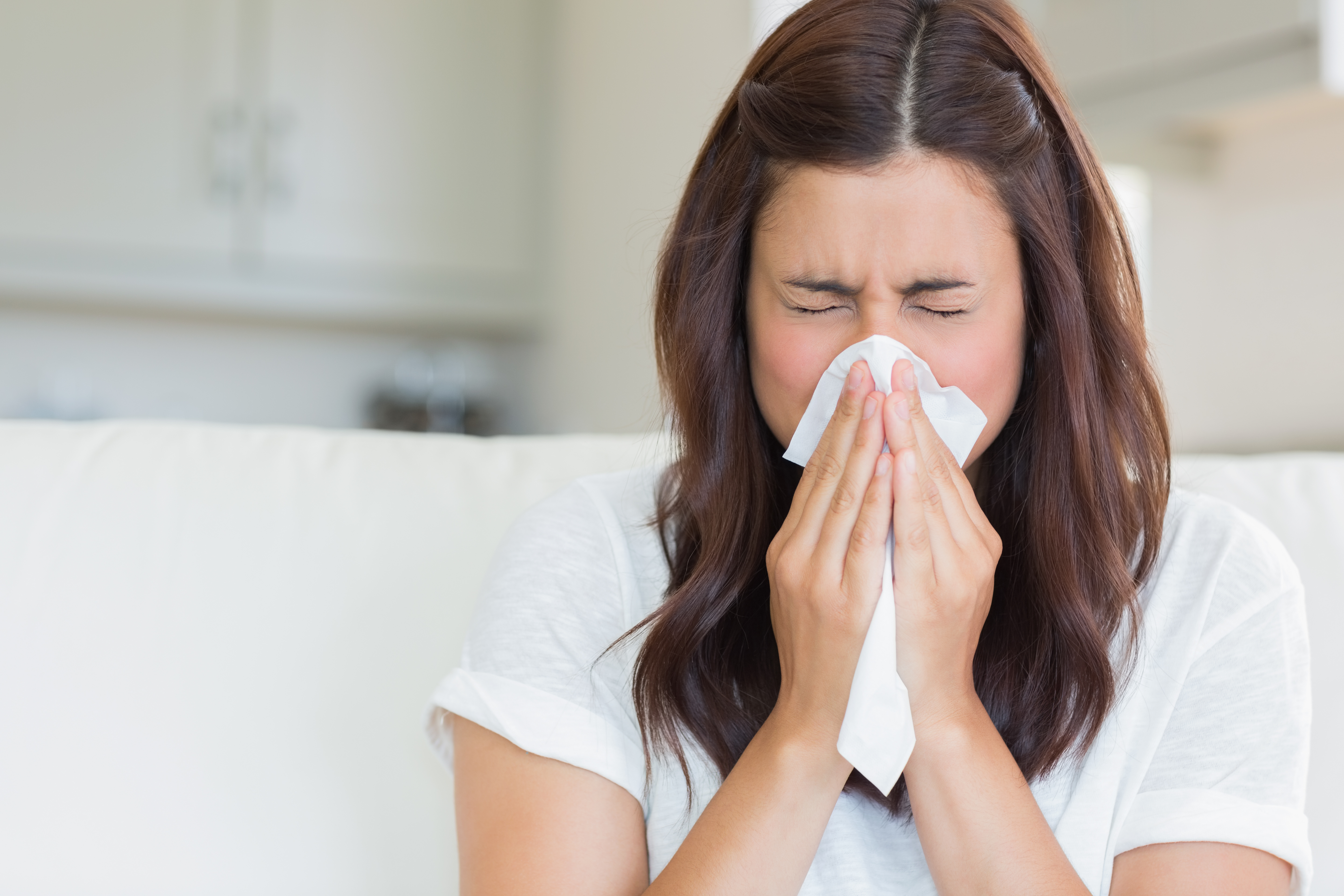 Una mujer estornudando con un pañuelo en la nariz y la boca | Fuente: Shutterstock