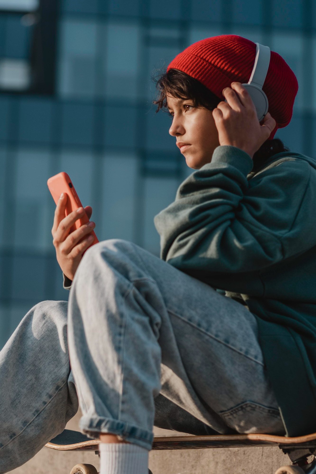 Un jeune garçon écoutant quelque chose sur ses écouteurs tout en tenant un téléphone | Source : Freepik
