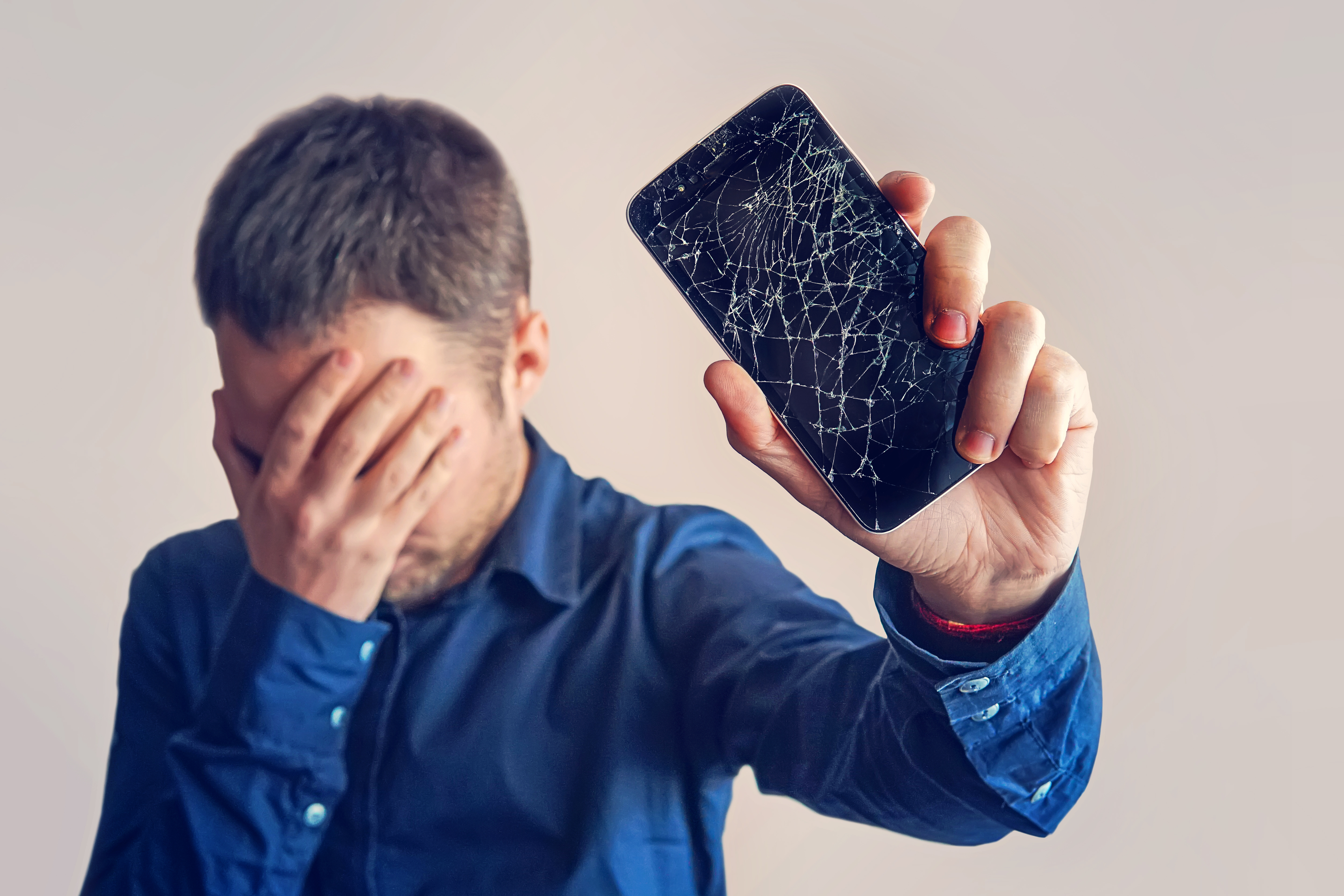 Un homme qui tient un téléphone dont l'écran est cassé | Source : Shutterstock