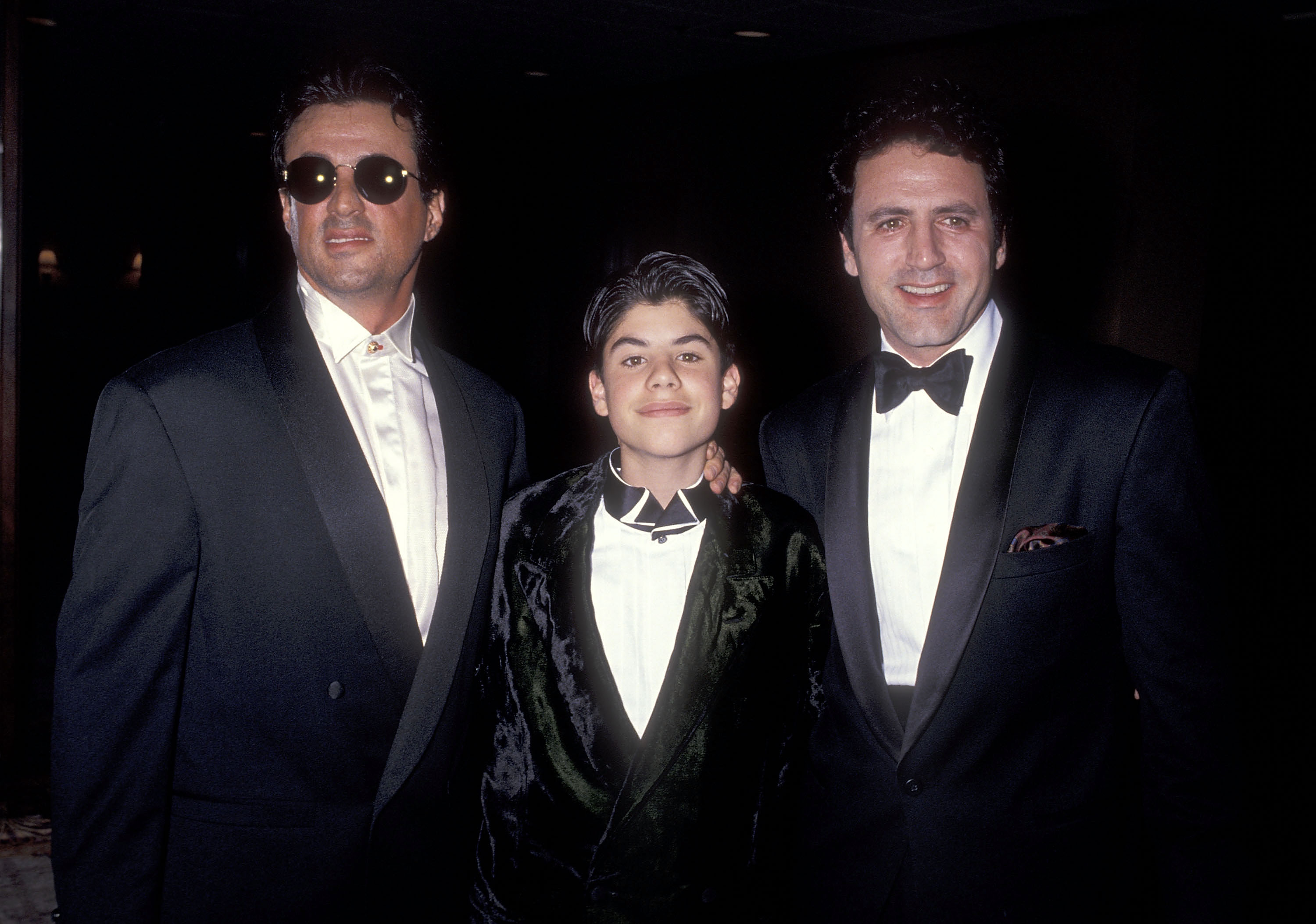 Le garçon, son père et son frère lors du cinquième défilé de mode annuel et du dîner de bienfaisance en hommage à Gianni Versace parrainé par les amis de l'industrie de la mode de Californie du projet de lutte contre le sida de Los Angeles à Century City le 13 février 1991 | Source : Getty Images