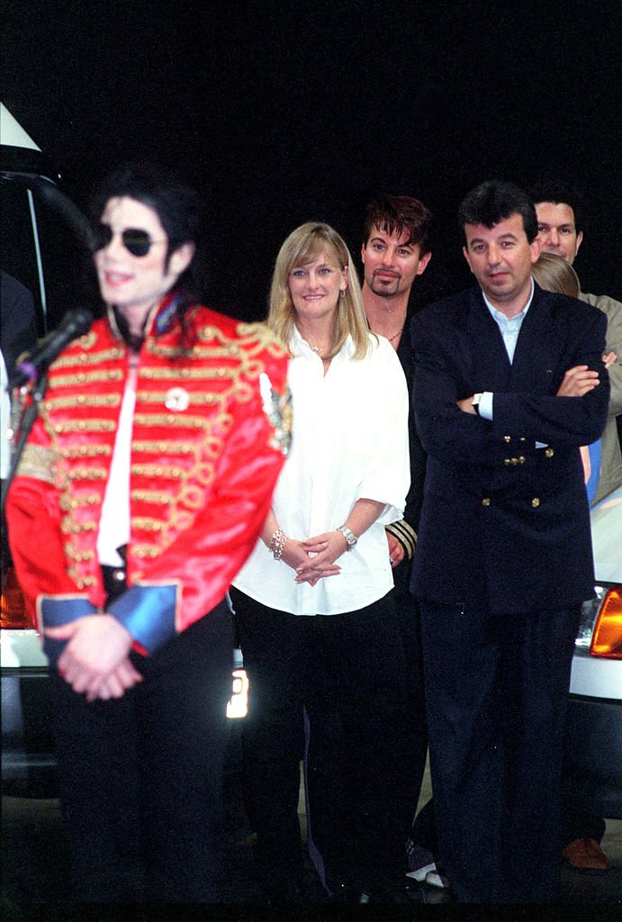 Le chanteur Michael Jackson signe des autographes pour ses fans sous le regard de sa femme Debbie Rowe, le 10 juillet 1997 à Sheffield, en Angleterre. | Photo : Getty Images