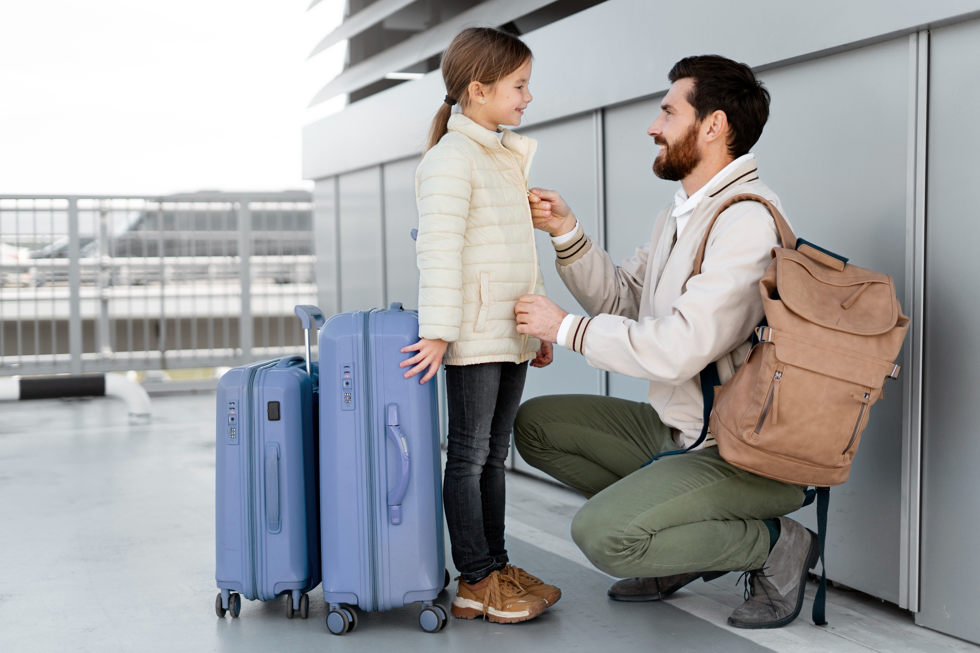 Un père et sa fille prêts pour leur voyage avec les bagages à la main | Source : Freepik