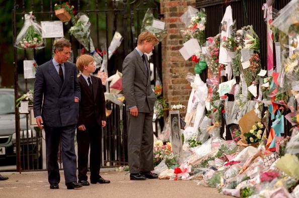 Le prince de Galles, le prince William et le prince Harry examinent des hommages floraux à Diana, princesse de Galles devant le palais de Kensington le 5 septembre 1997 à Londres, en Angleterre. | Photo : Getty Images.