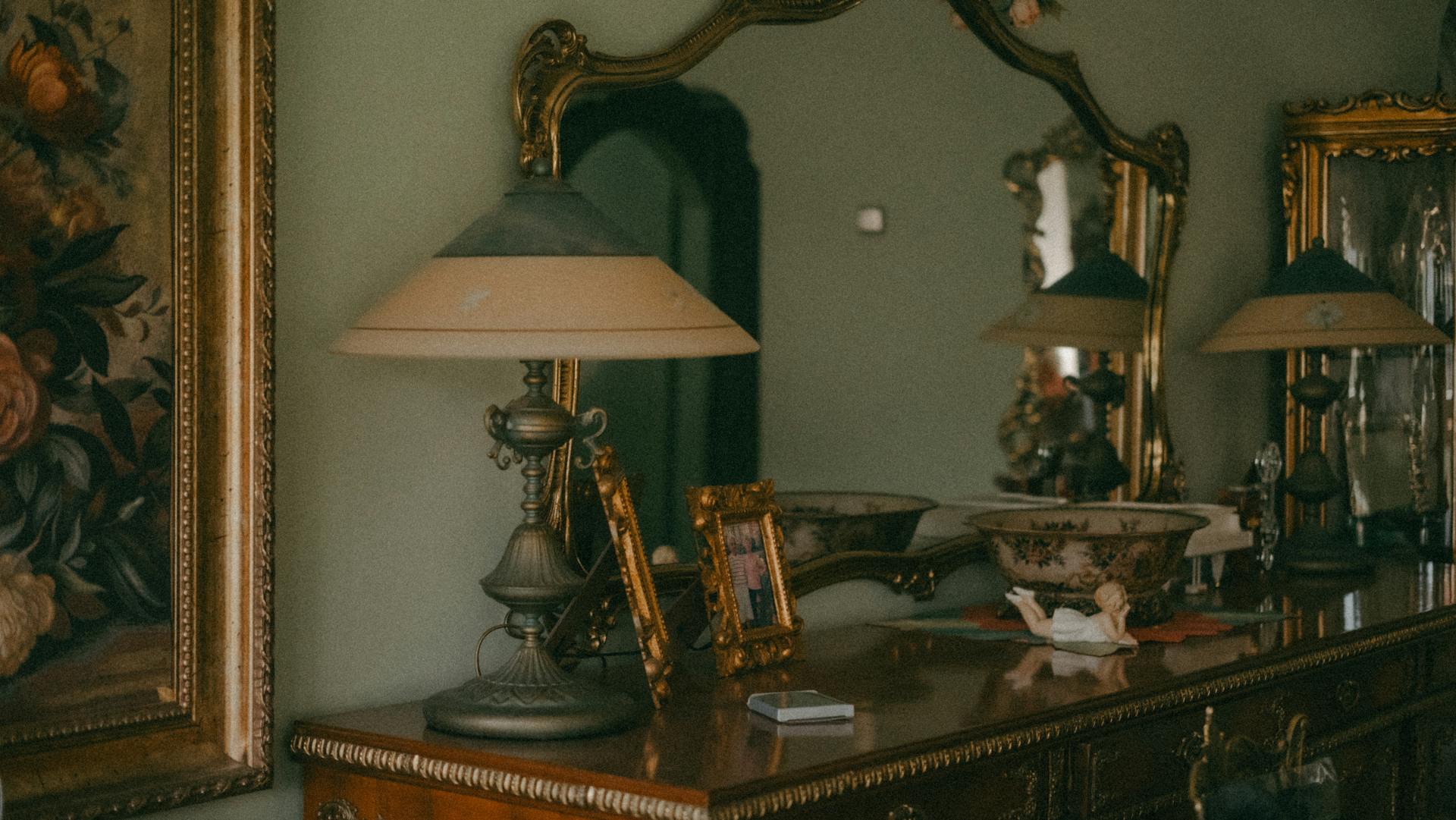 Une commode antique en bois avec une lampe et des cadres dorés sur le dessus | Source : Pexels