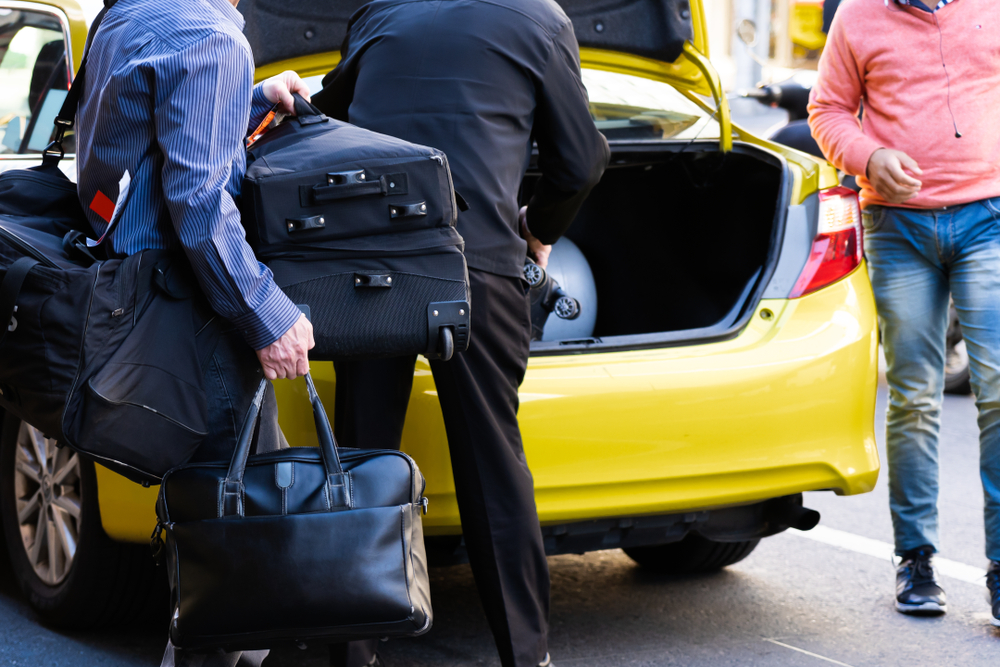 Pasajeros cargando sus maletas en el maletero de un taxi. | Fuente: Shutterstock