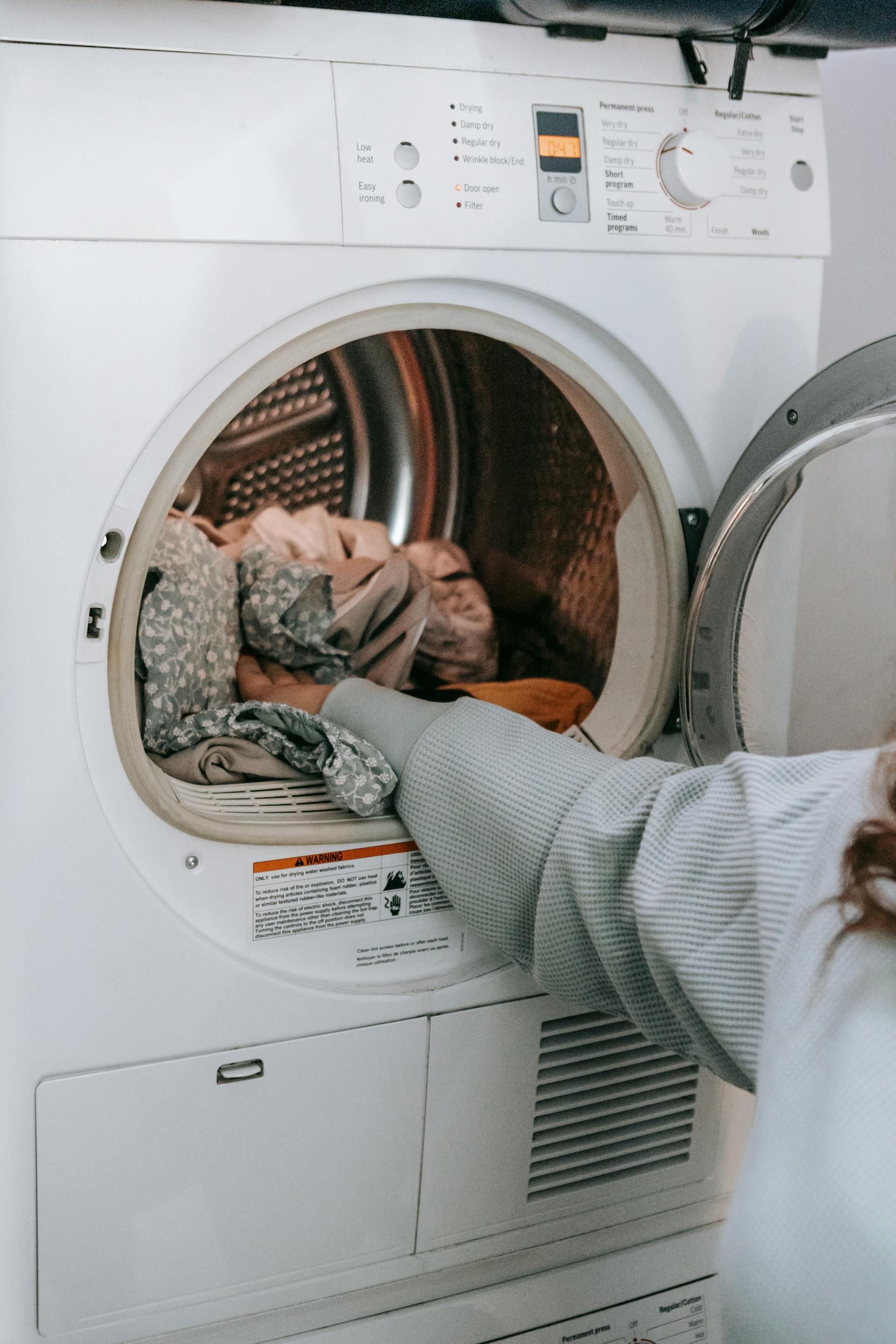 Une femme chargeant des vêtements dans une machine à laver | Source : Pexels