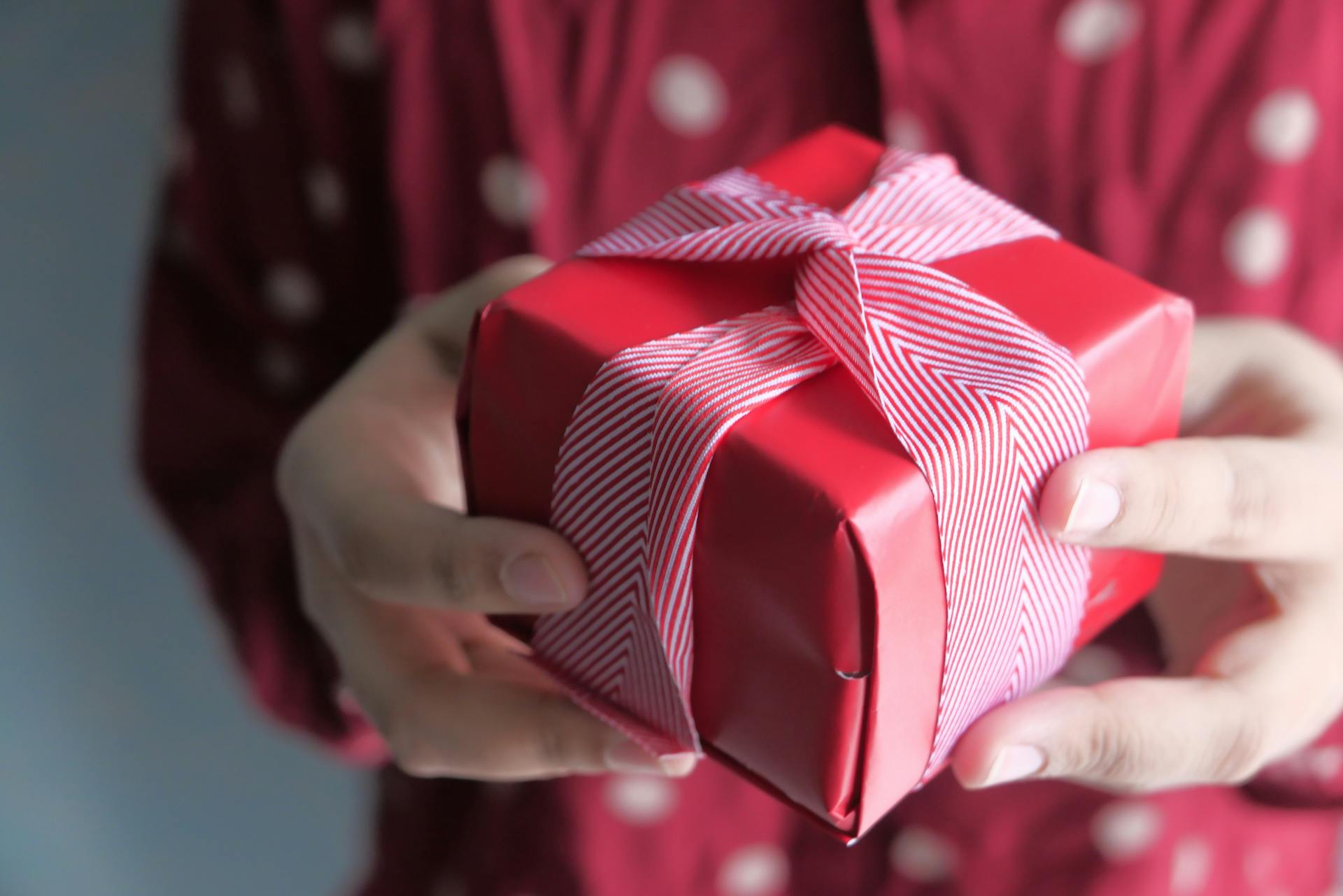 Une femme tendant une petite boîte emballée de cadeaux | Source : Pexels