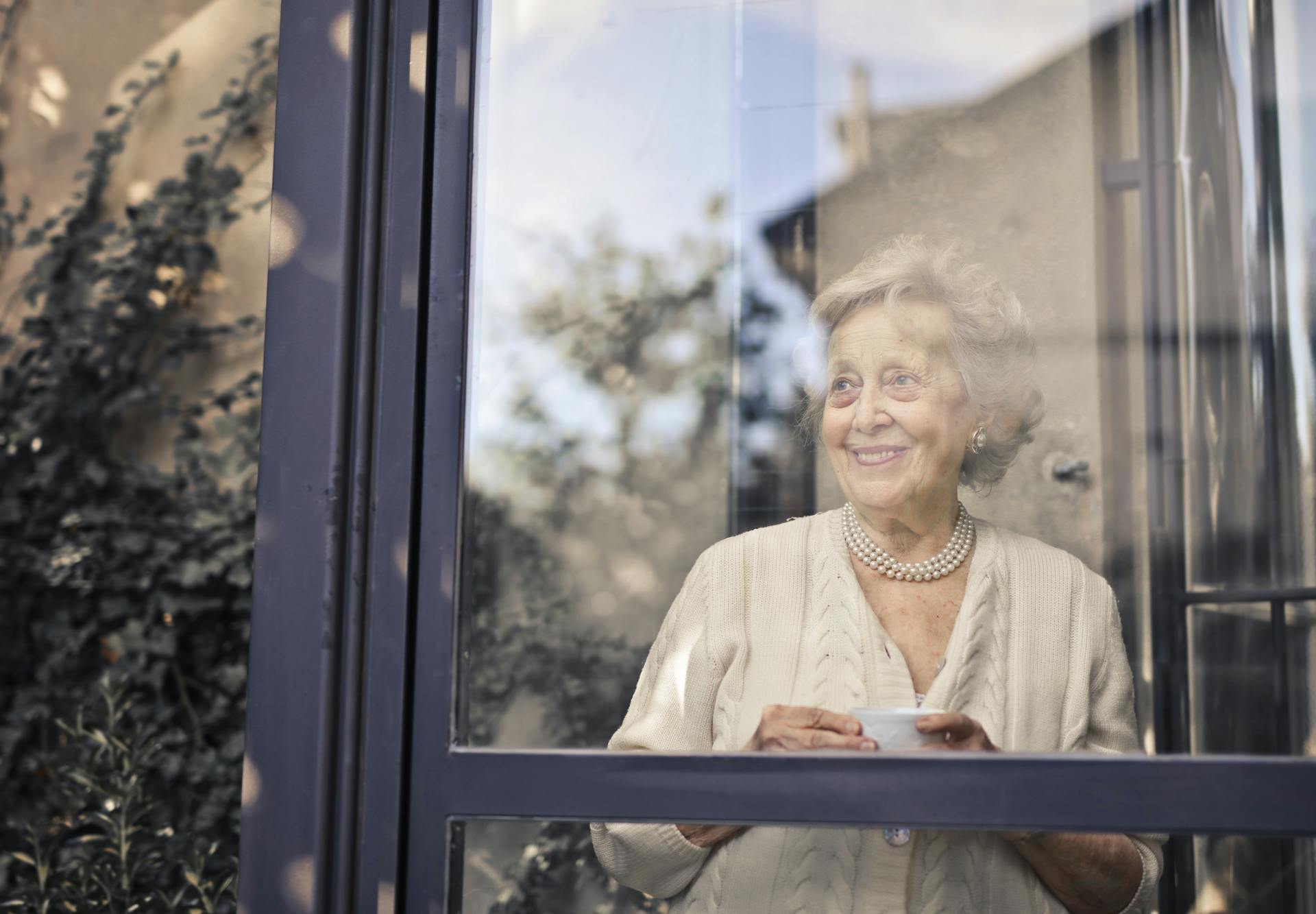 Une femme âgée debout devant une fenêtre en verre | Source : Pexels