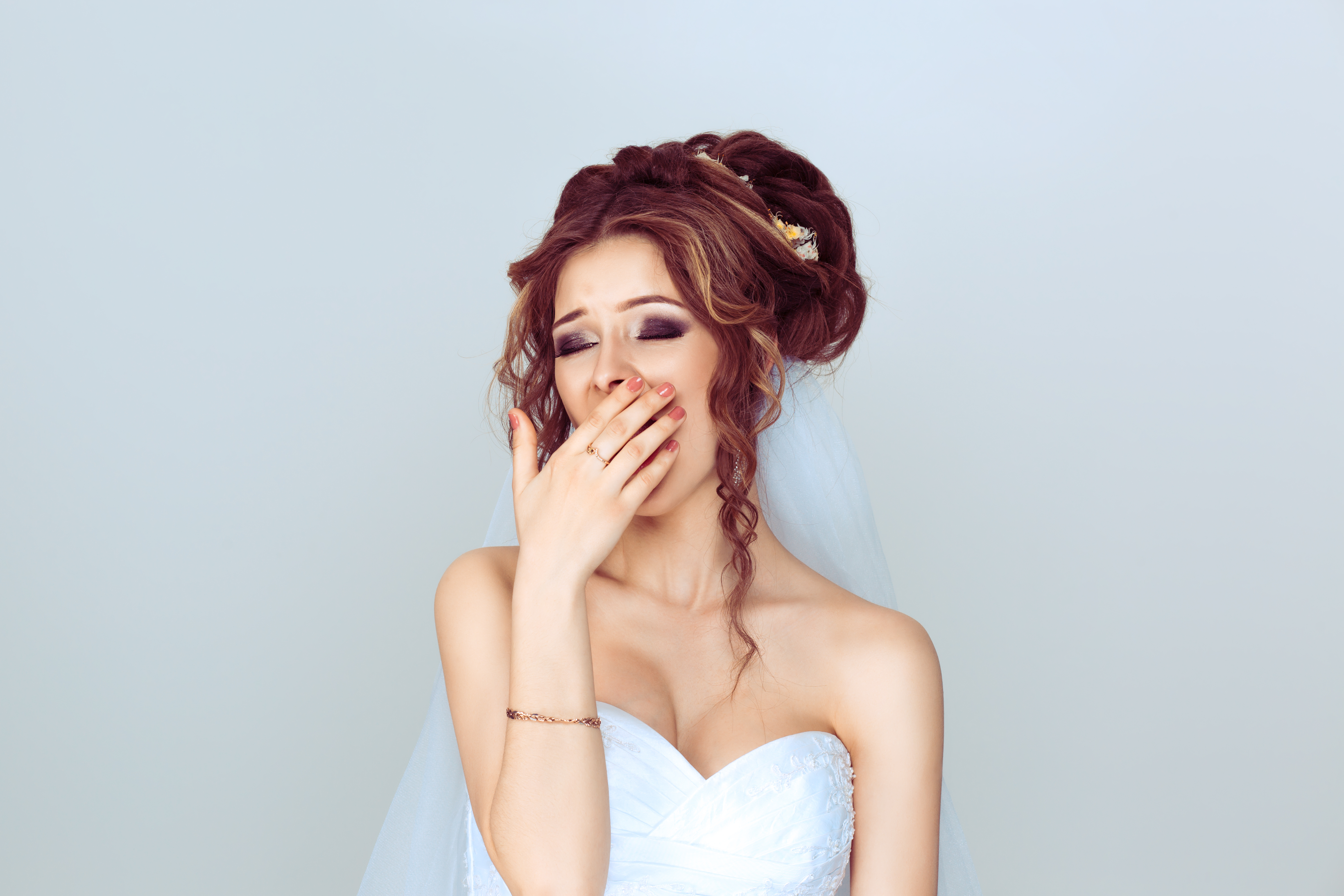 Une mariée se couvre la bouche en baillant | Source : Shutterstock