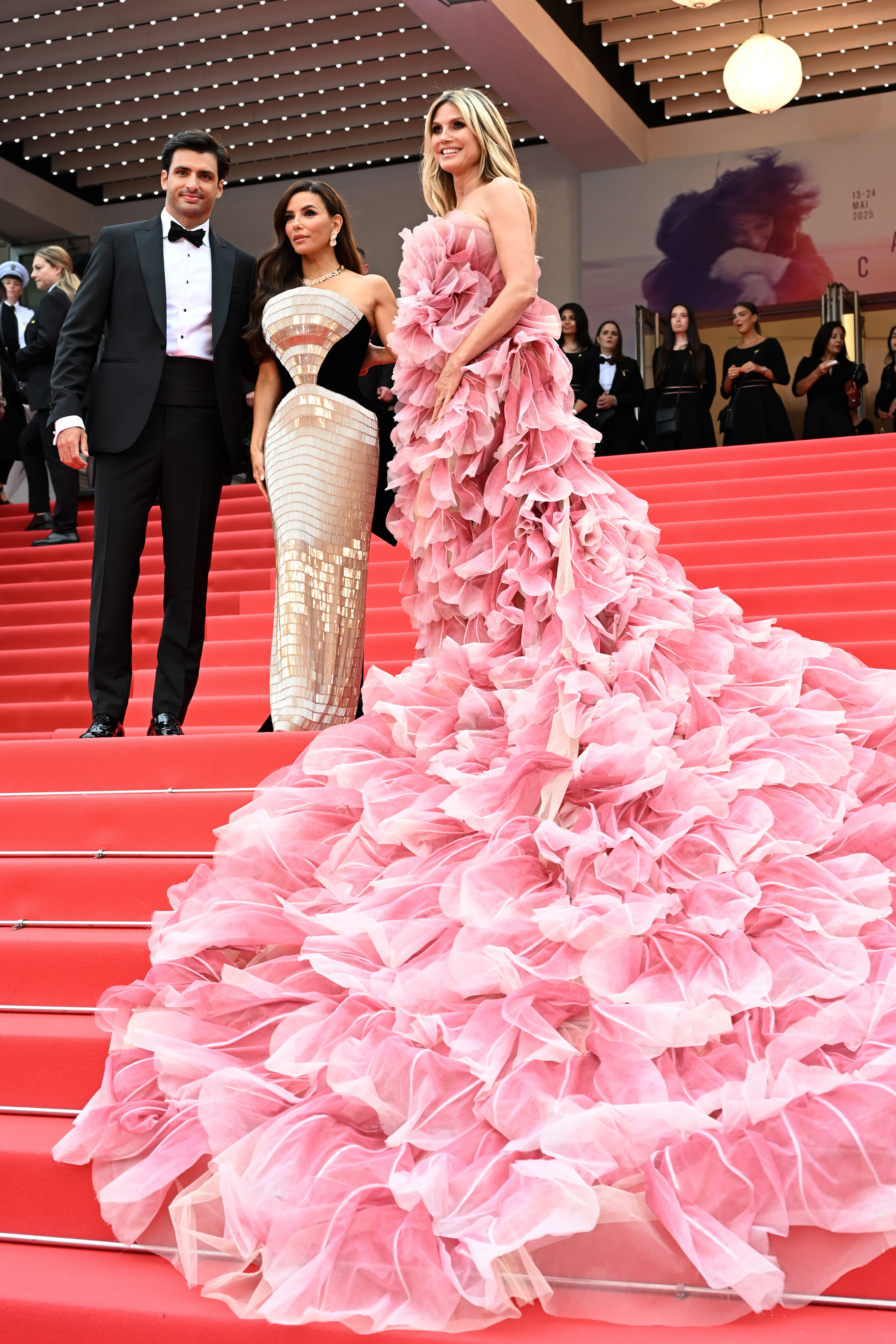 La beauté et la virilité se rencontrent dans un cliché captivant où Heidi Klum pose sur les marches aux côtés d'un fringant Carlos Sainz Jr. et de l'éternelle glamour Eva Longoria - un trio qui illumine l'image sans le moindre effort.