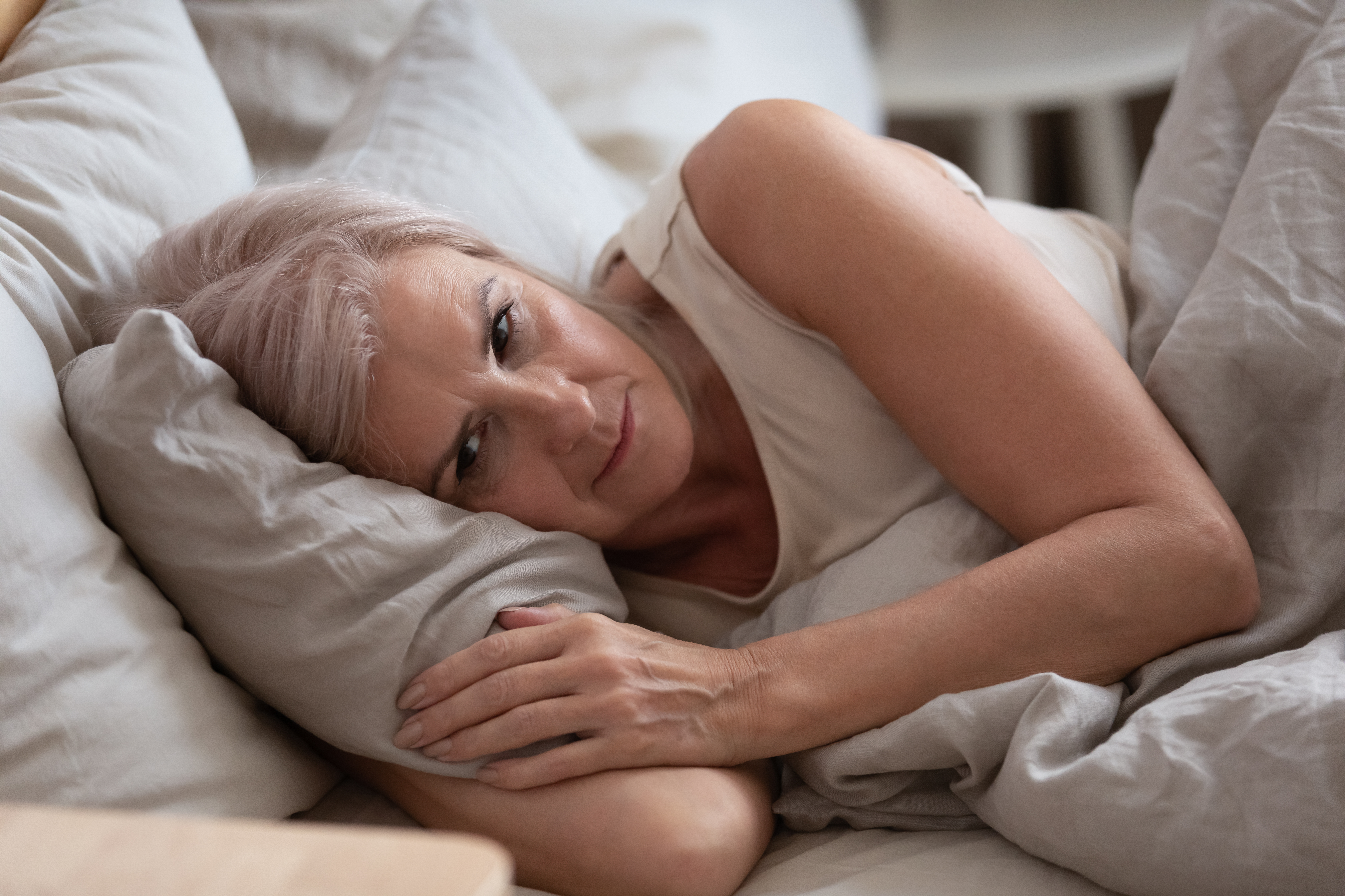 Une femme en proie à de profondes pensées alors qu'elle est allongée dans son lit | Source : Shutterstock