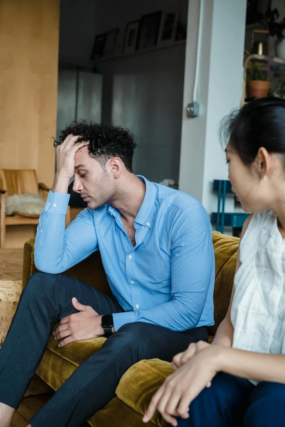 A woman talking to her tired husband on their couch | Source: Pexels