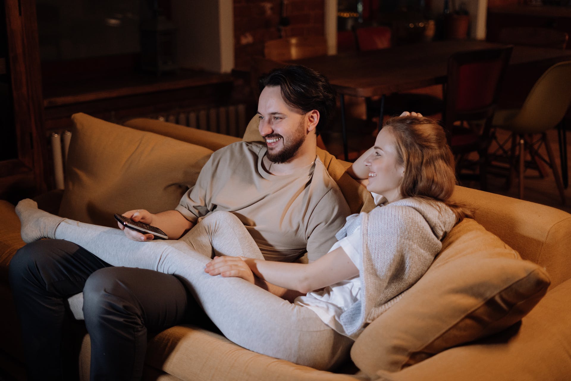 Un couple se câline en regardant la télévision à la maison | Source : Pexels