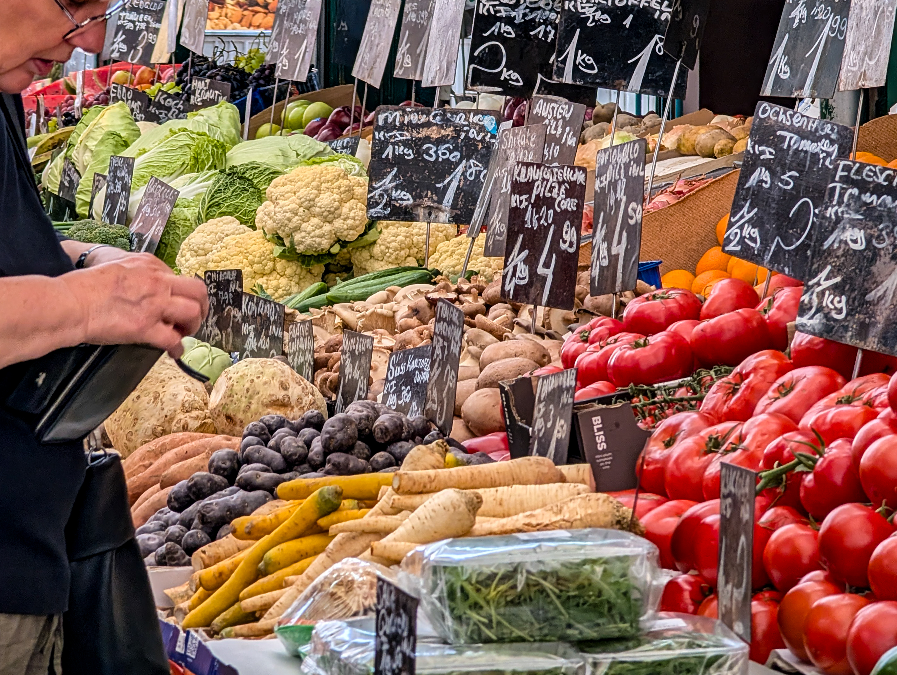 Des légumes frais et des panneaux de prix écrits à la main sont exposés sur un étal de marché | Source : Getty Images
