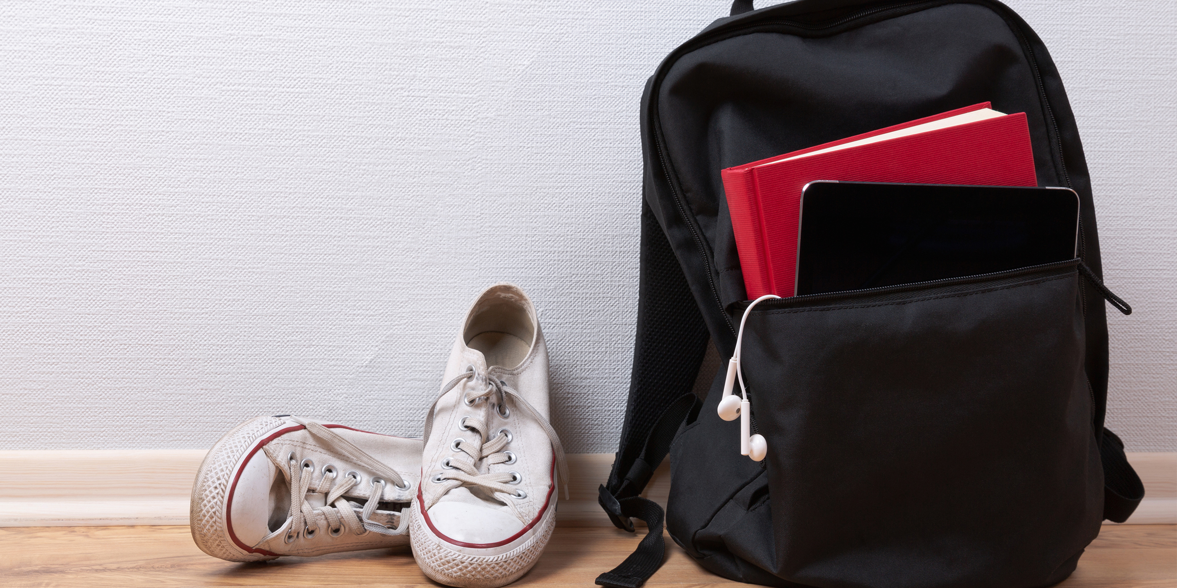 Un sac à dos noir à côté d'une paire de baskets blanches | Source : Shutterstock