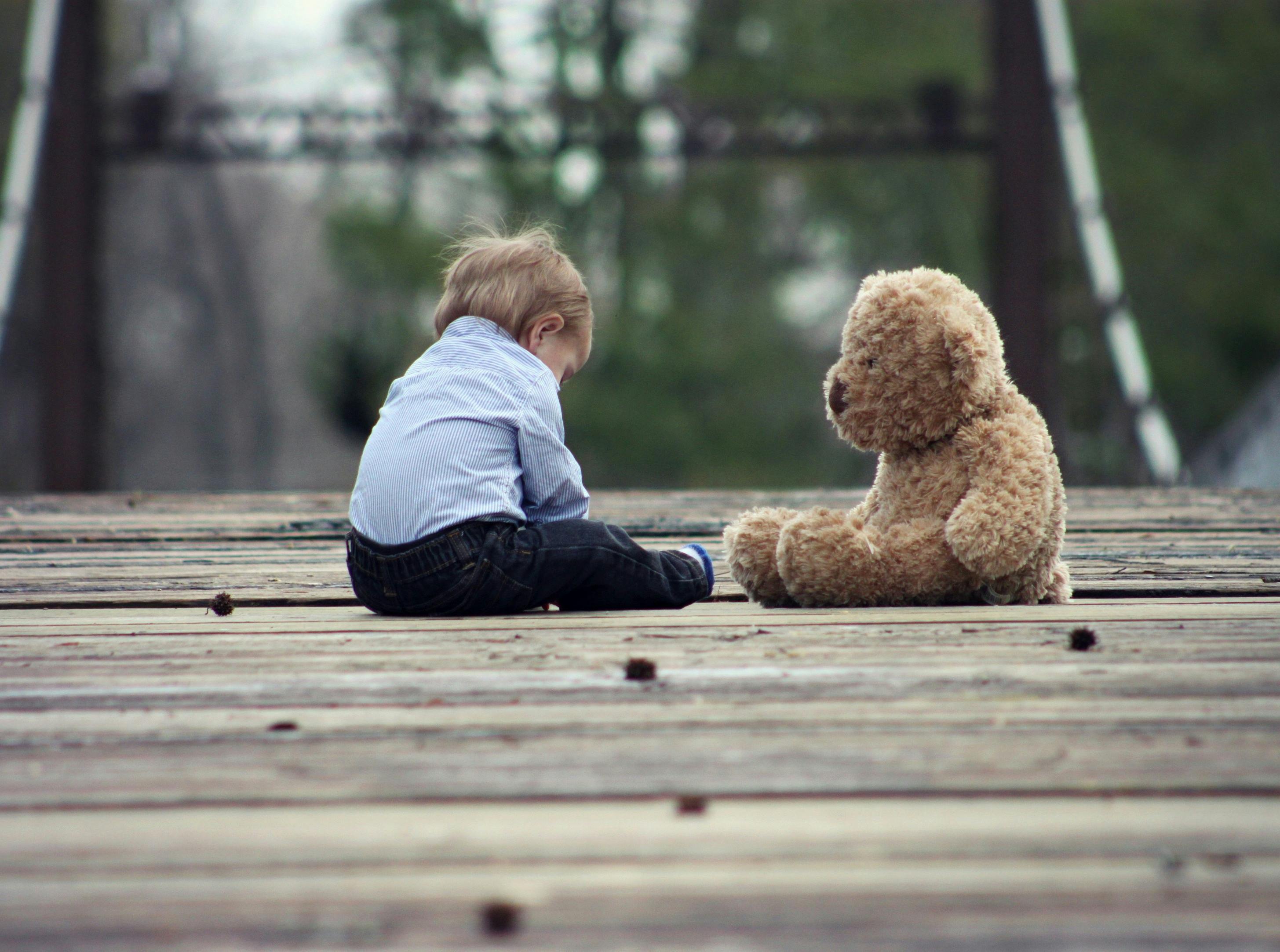 Un enfant triste assis à côté d'un ours en peluche | Source : Pexels