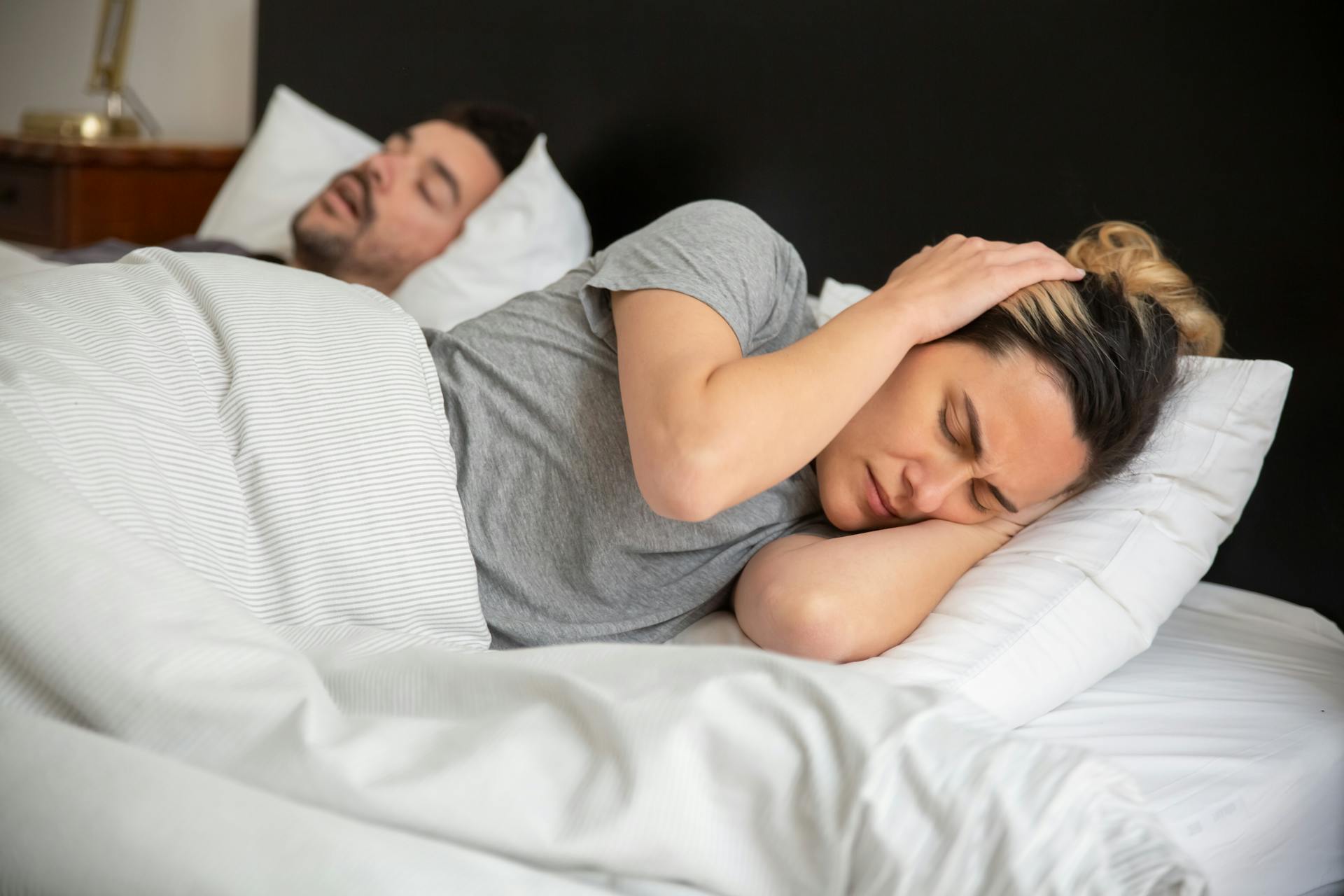 Une femme au lit se couvrant les oreilles avec ses mains | Source : Pexels
