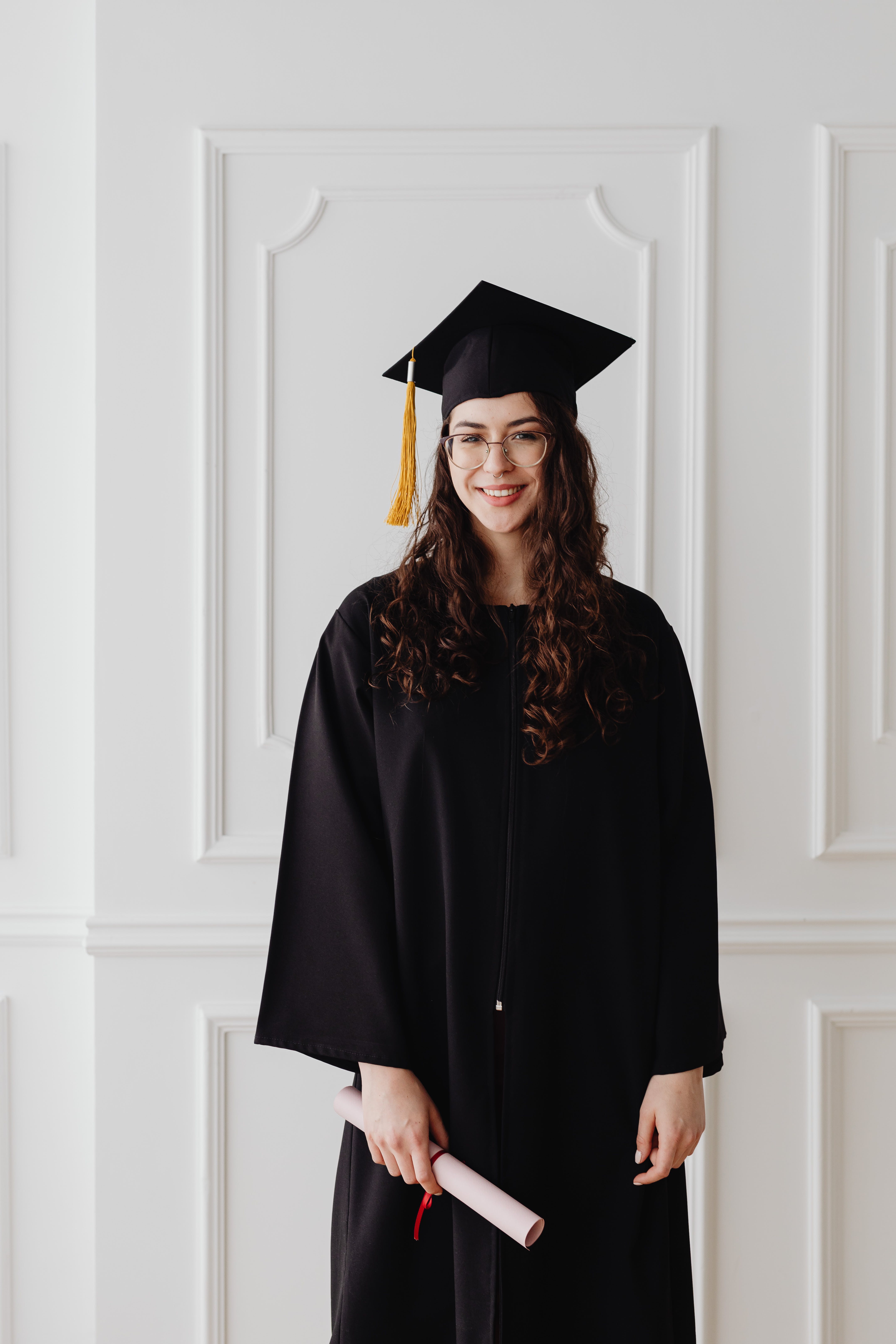 Une femme sourit alors qu'elle pose en tenue de diplômée | Source : Pexels