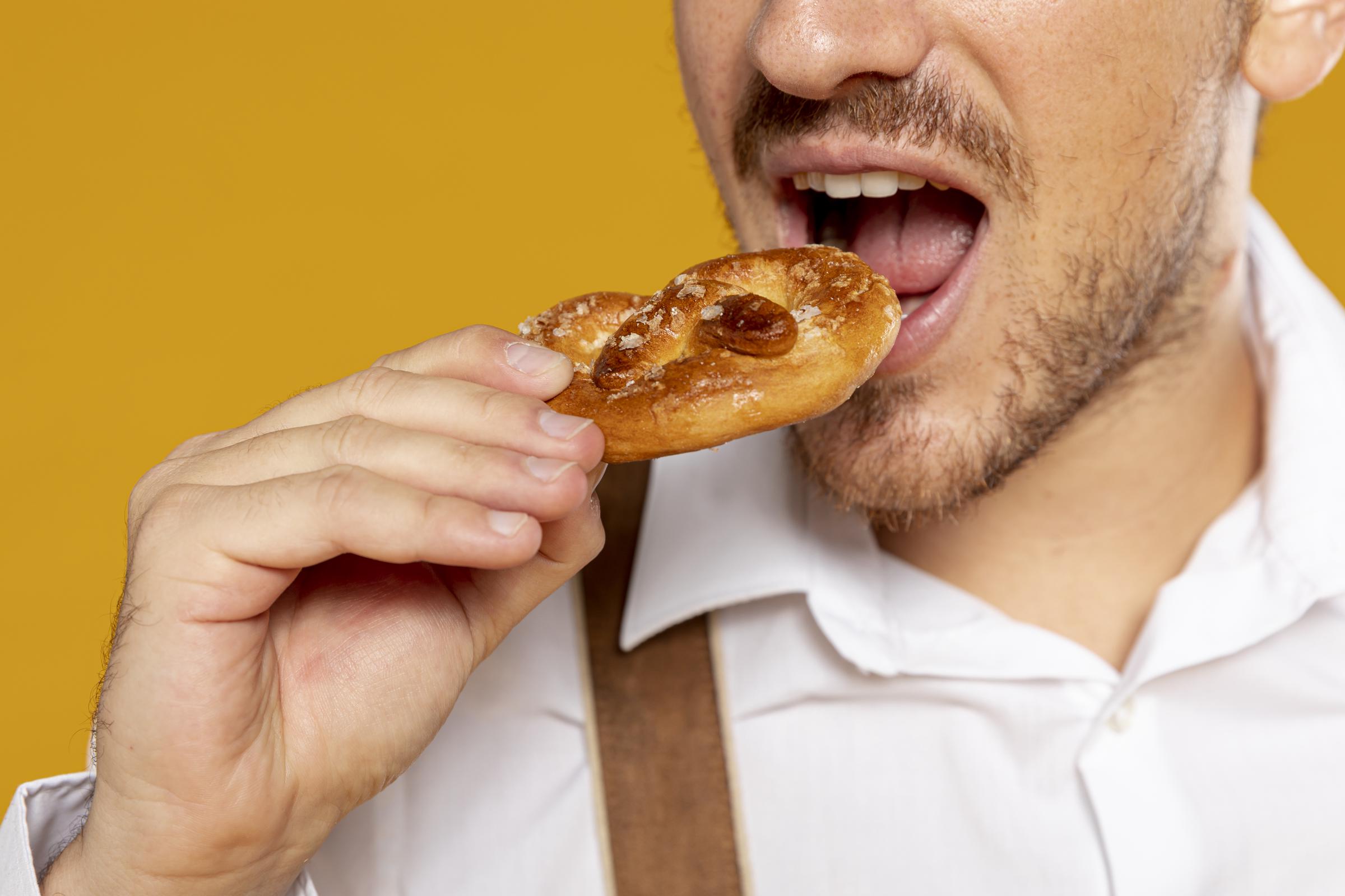 Gros plan d'un homme qui mange un bretzel | Source : Freepik